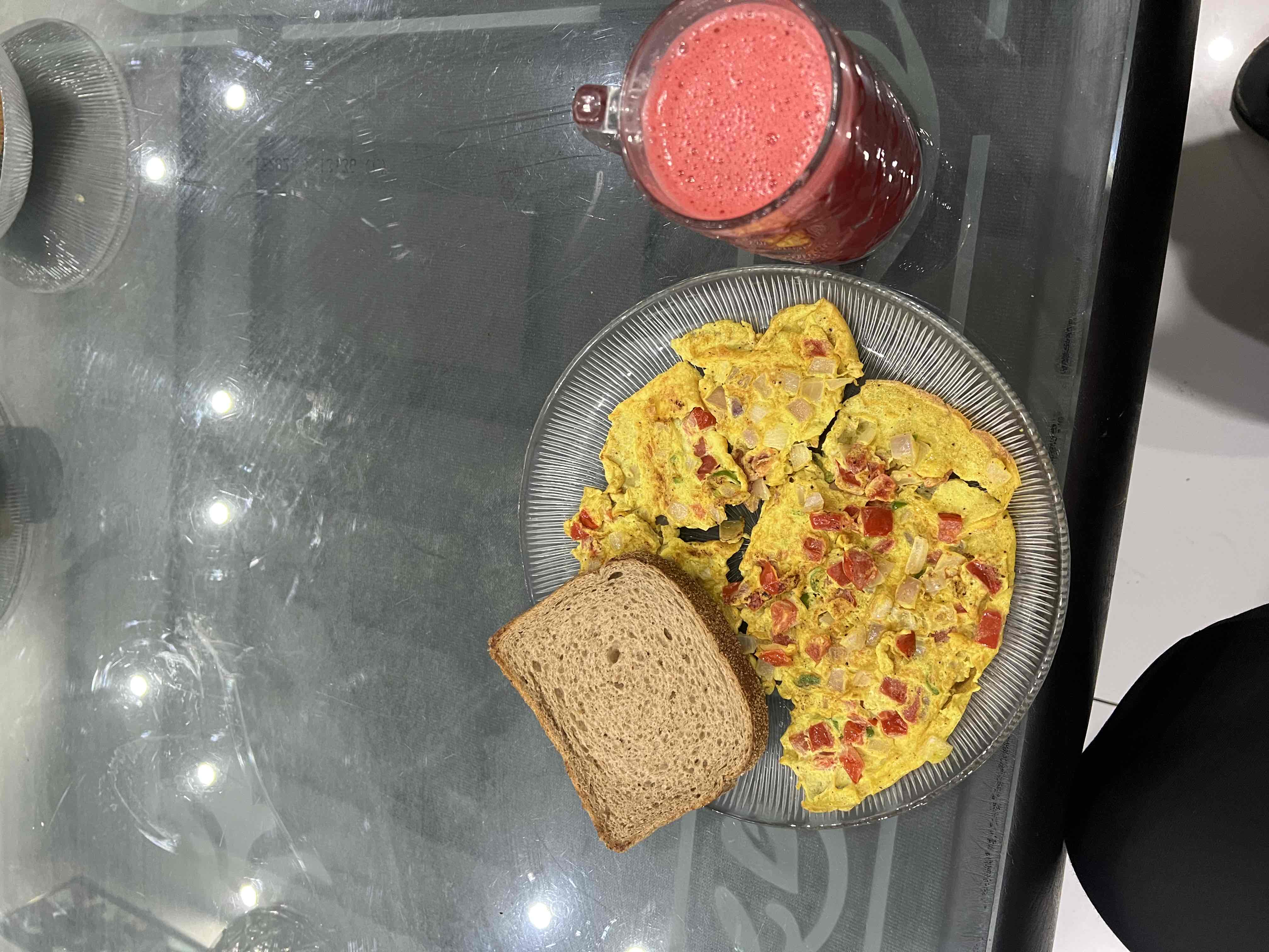 A balanced meal consisting of a vegetable omelette, a slice of whole wheat bread, and a strawberry smoothie.