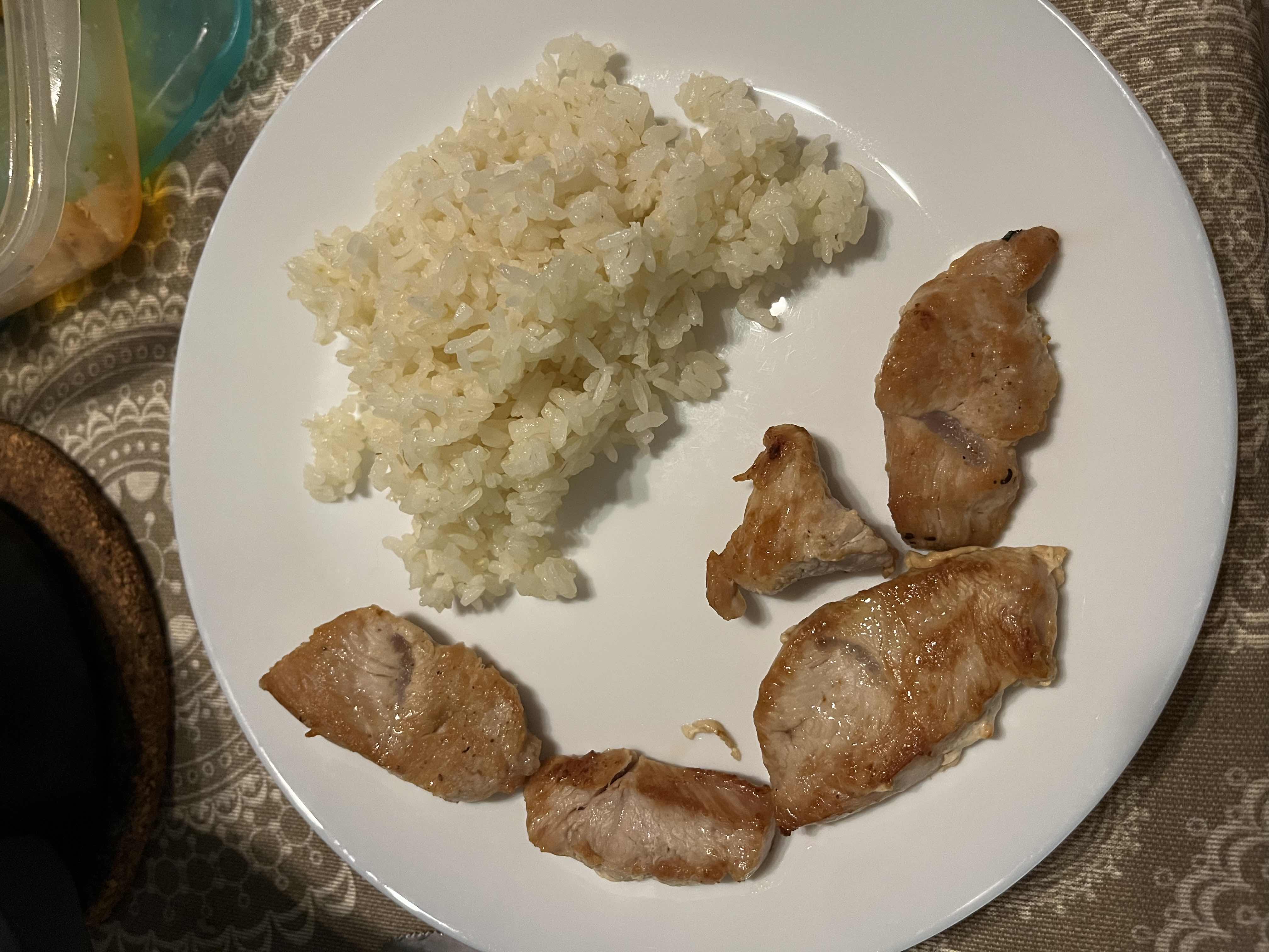 A plate containing grilled chicken and white rice, providing a balanced meal with moderate calories and protein.