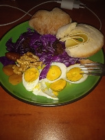 A balanced meal consisting of boiled eggs, red cabbage, walnuts, and bread, providing a mix of protein, carbs, and healthy fats.