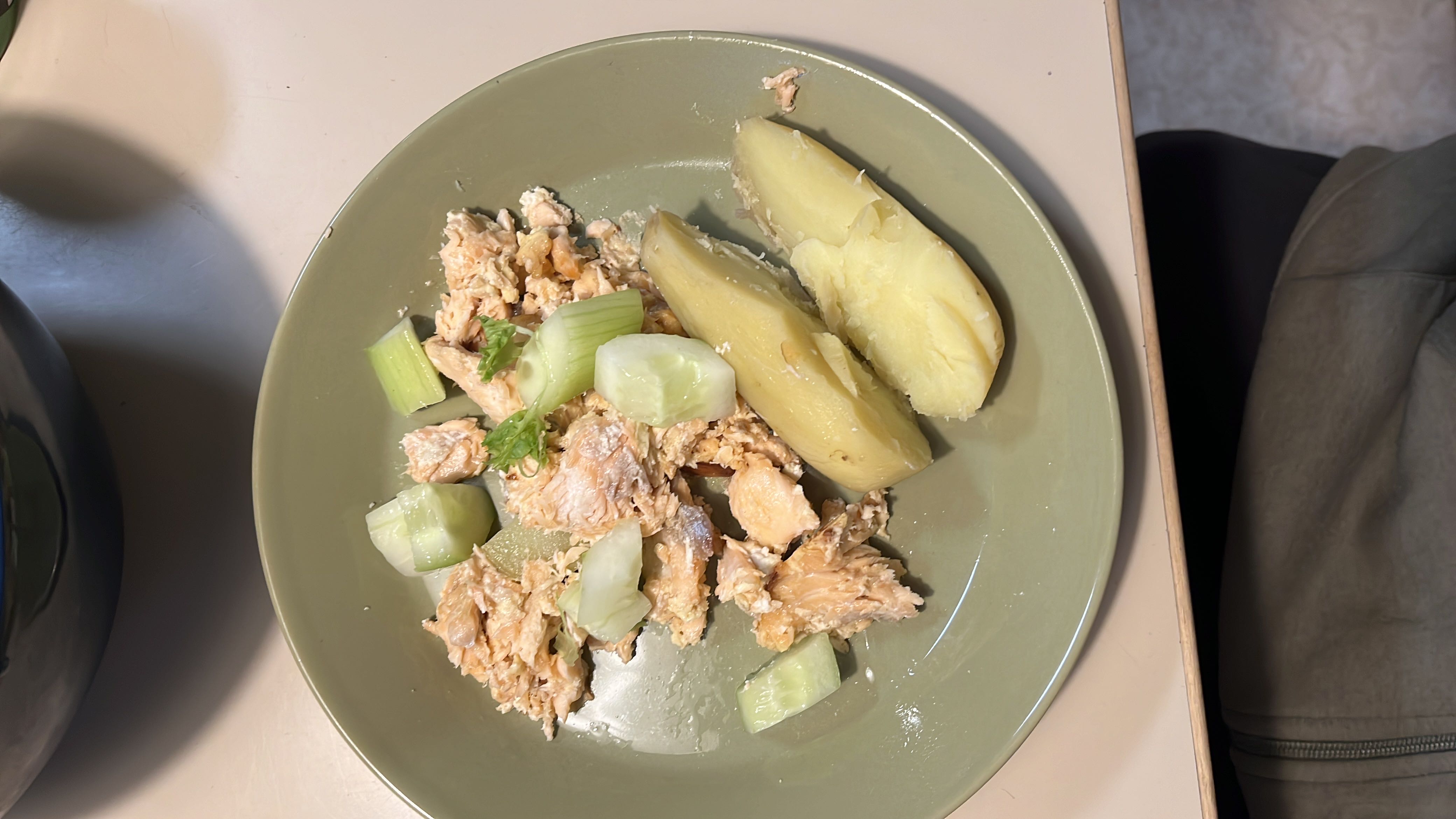 A balanced meal consisting of salmon, boiled potato, and cucumber, providing a good mix of protein, carbs, and healthy fats.