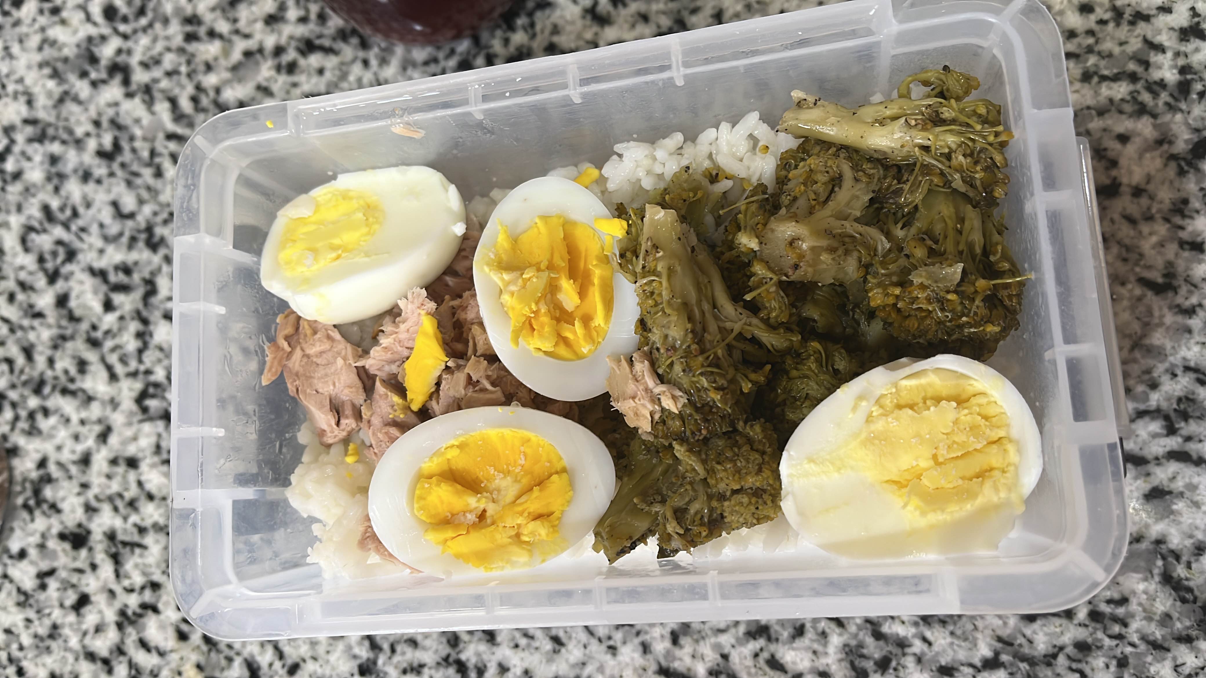 A balanced meal consisting of boiled eggs, broccoli, tuna, and white rice, providing a good mix of protein, carbs, and fats.