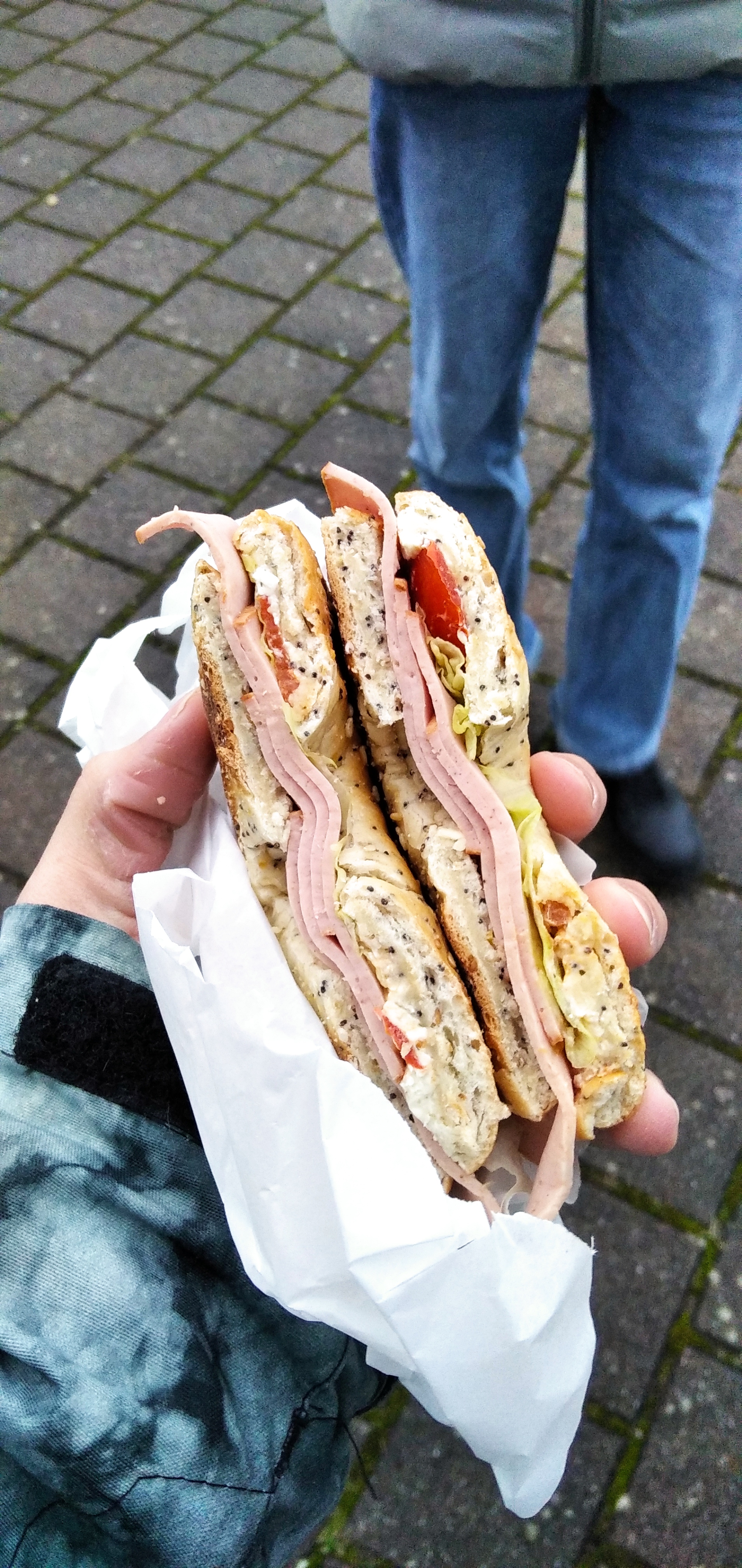A sandwich made with whole grain bread, ham, lettuce, tomato, and cream cheese, providing a balanced mix of protein, carbs, and fats.