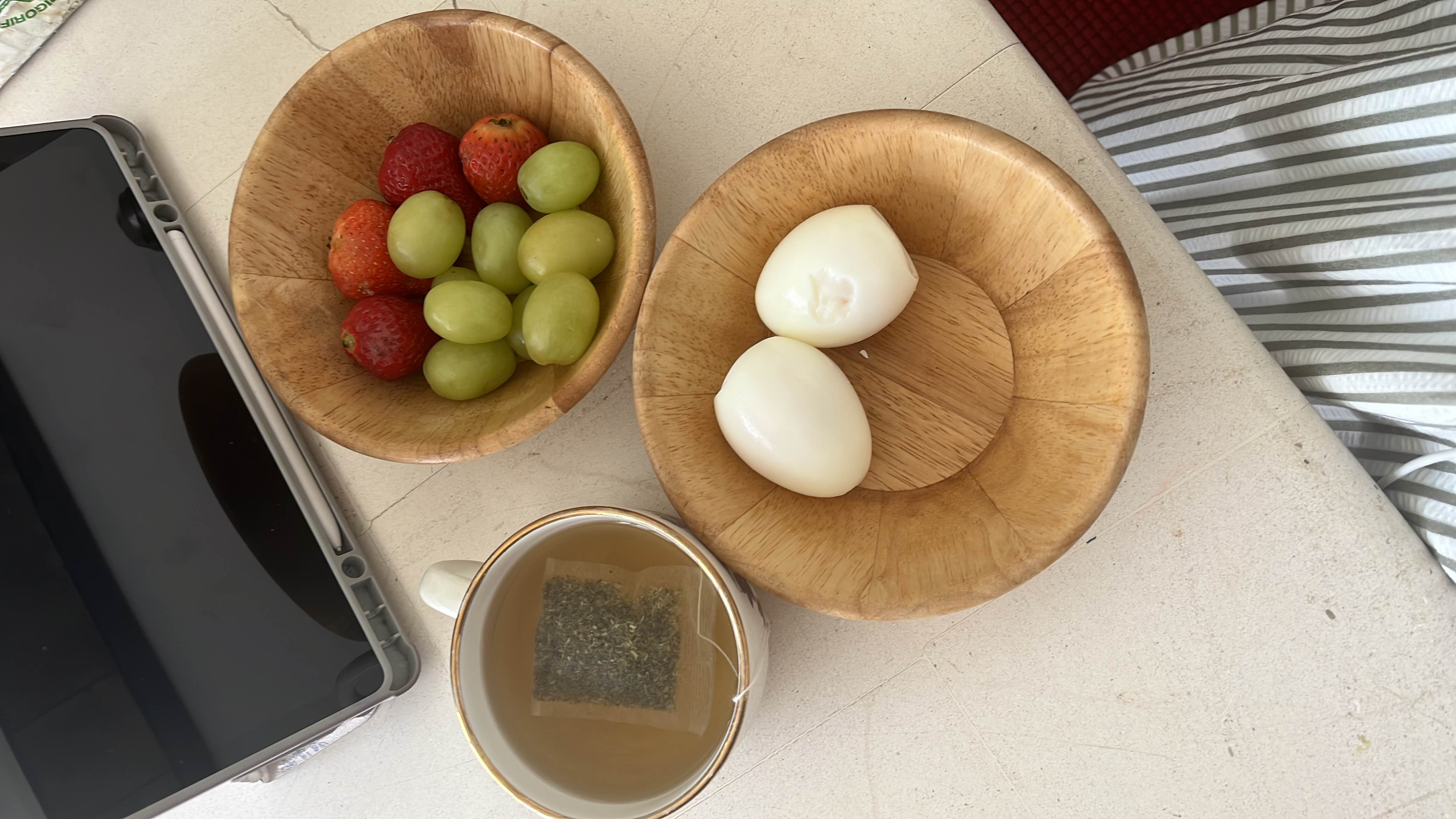 A light meal consisting of boiled eggs, strawberries, grapes, and green tea, providing a balanced mix of protein, carbs, and fats.