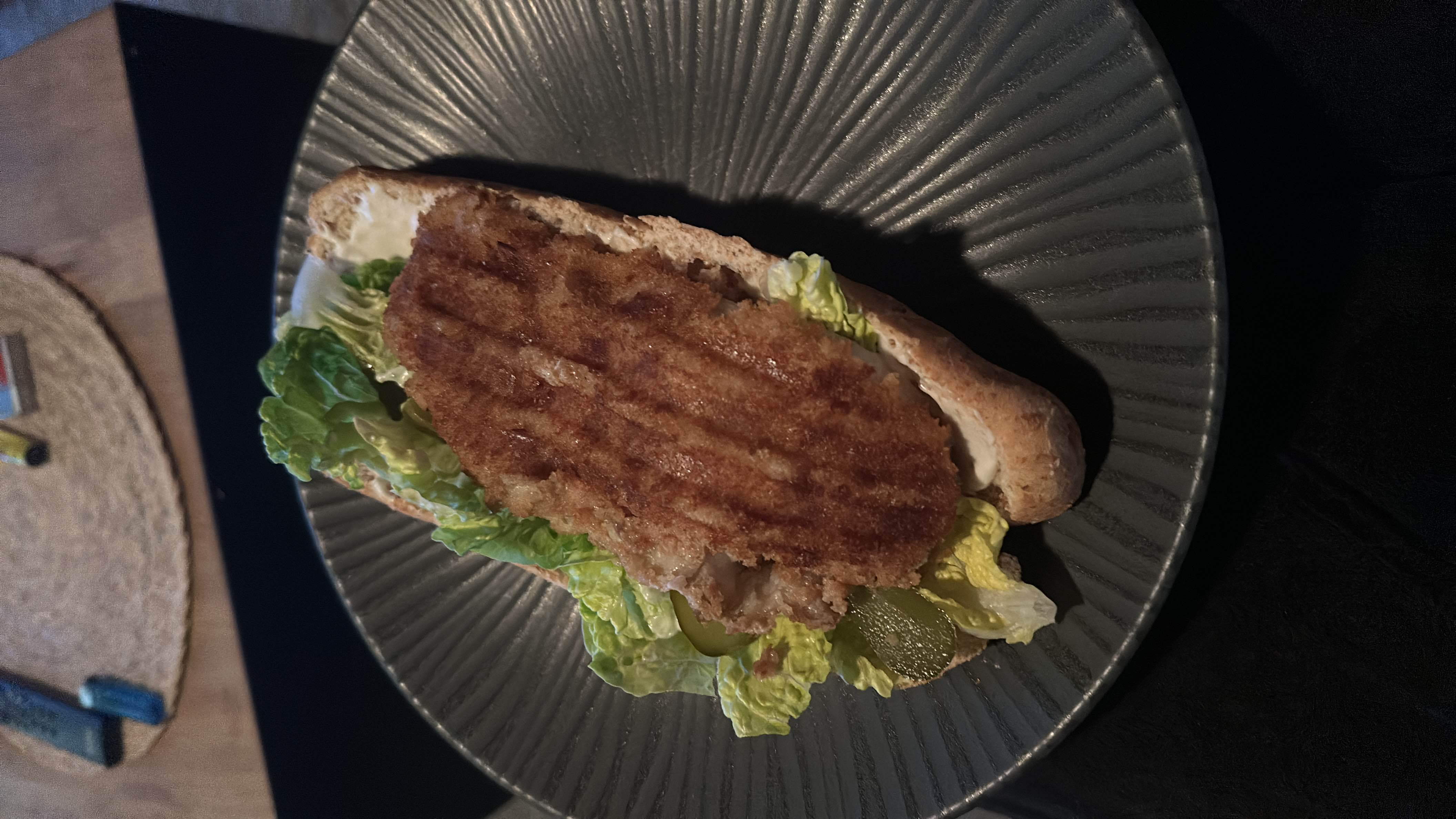 A sandwich with bread, lettuce, pickles, Seelachfilet, and light mayonnaise, offering a healthier balance of protein, carbs, and fats.