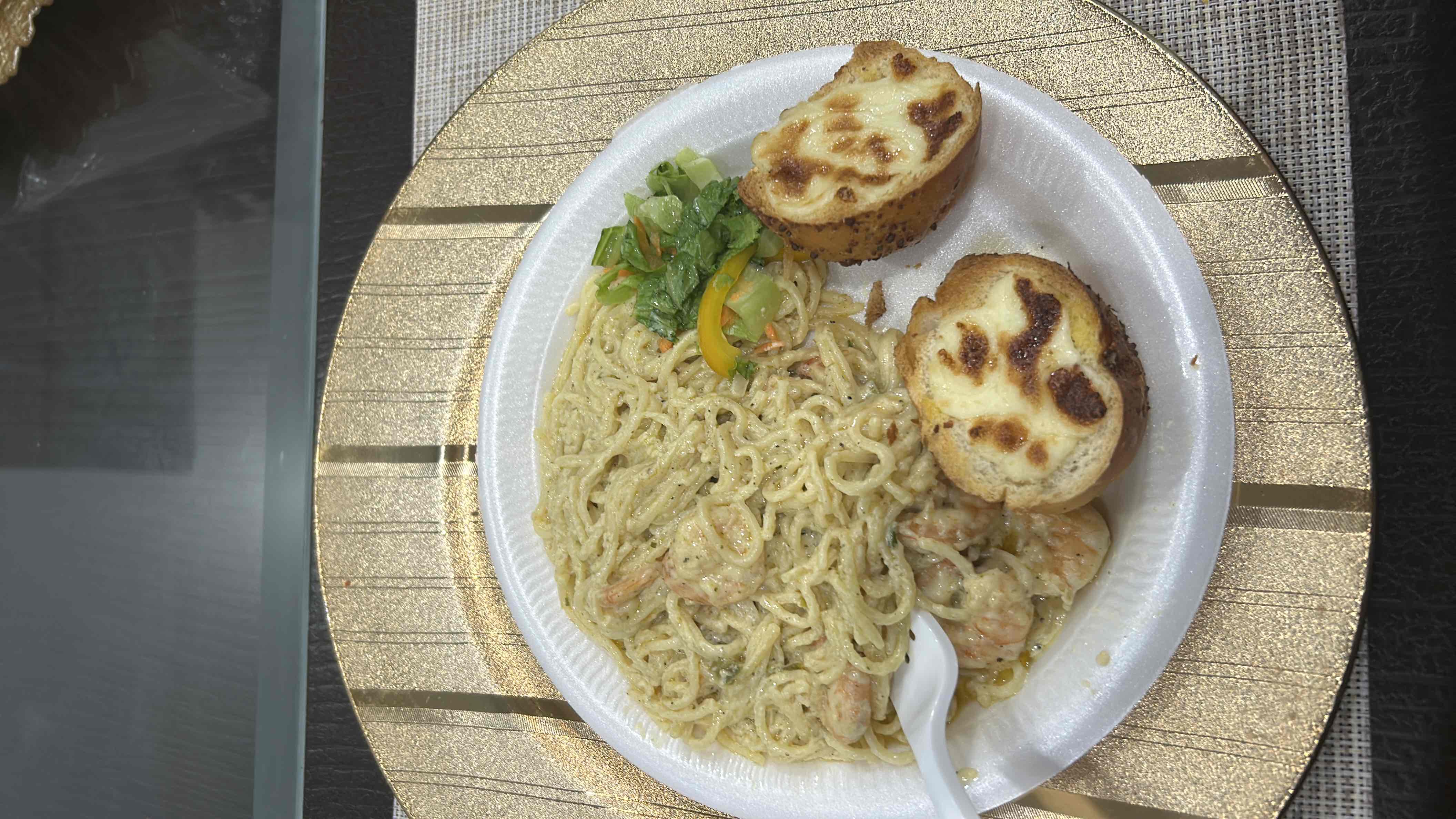 A plate of creamy shrimp spaghetti served with cheese bread and a side of fresh salad.