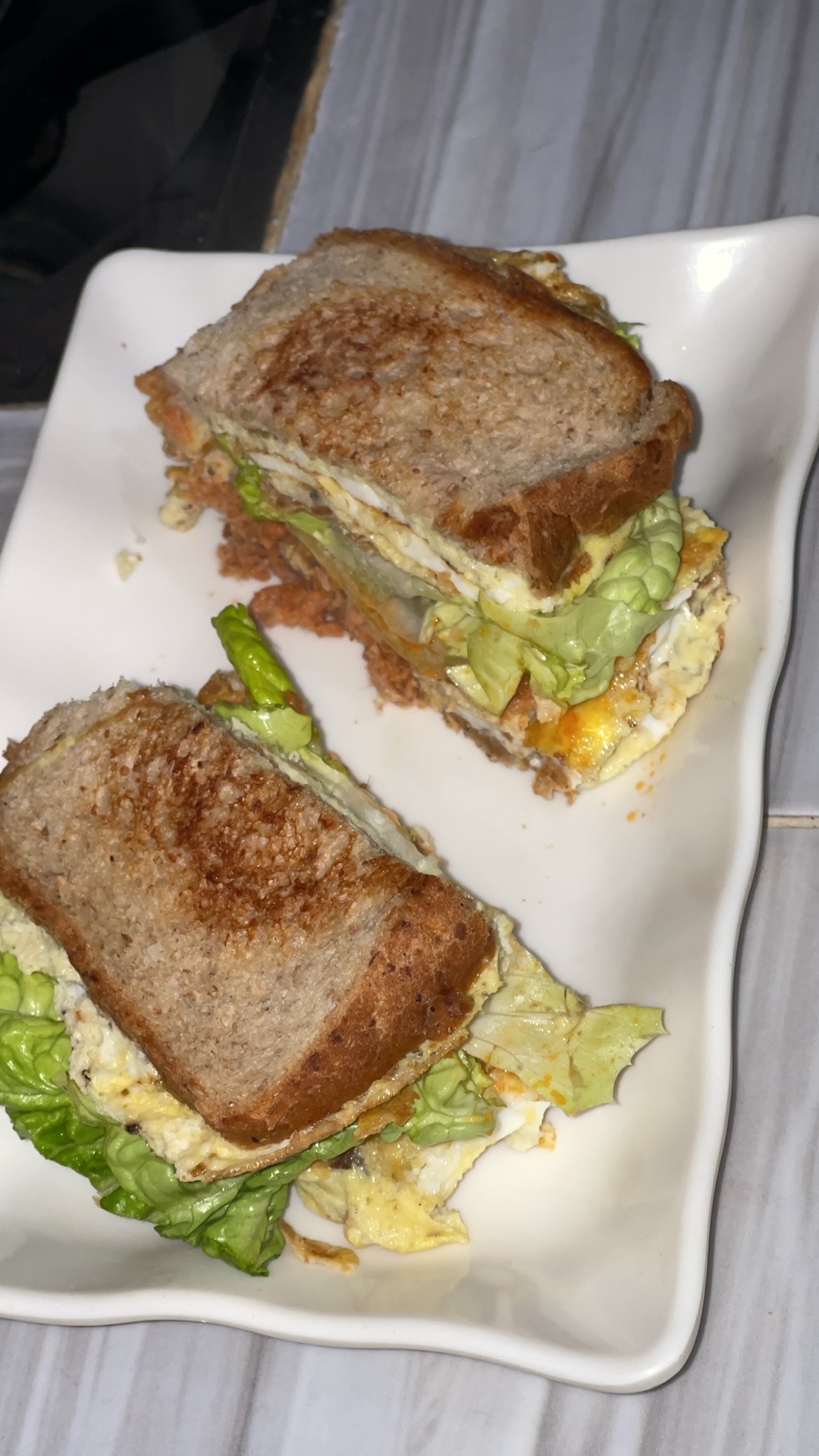 A healthy sandwich made with whole grain bread, lettuce, egg, cheese, and avocado, providing a balanced mix of protein, carbs, and fats.