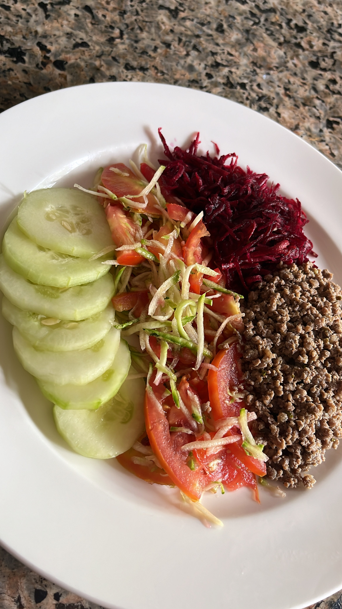 A healthy plate consisting of sliced cucumber, tomato, grated beetroot, and cooked ground meat, providing a balanced mix of protein, carbs, and fats.