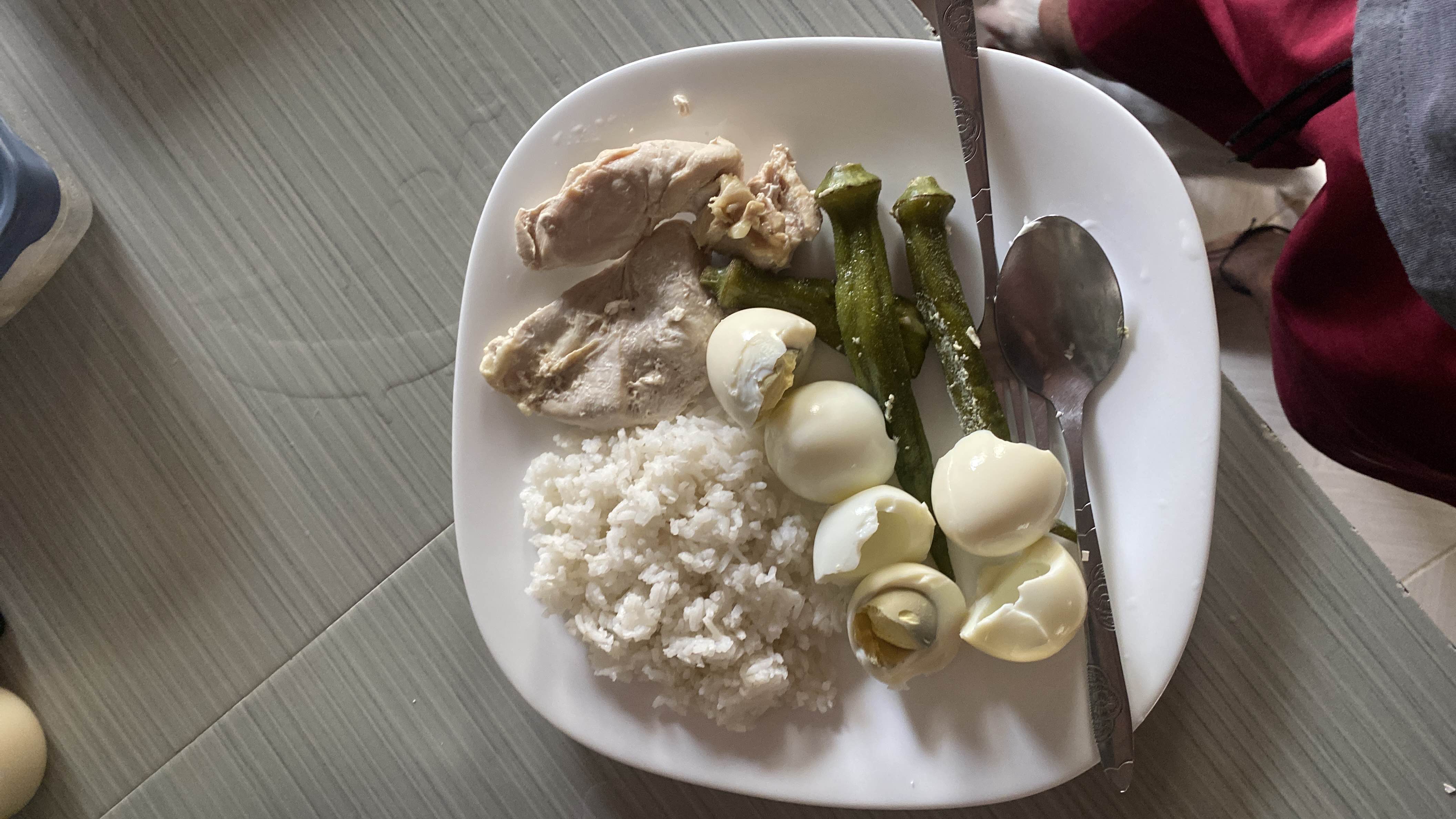 A balanced meal consisting of boiled eggs, steamed okra, boiled chicken breast, and white rice, providing a good mix of protein, carbs, and fats.