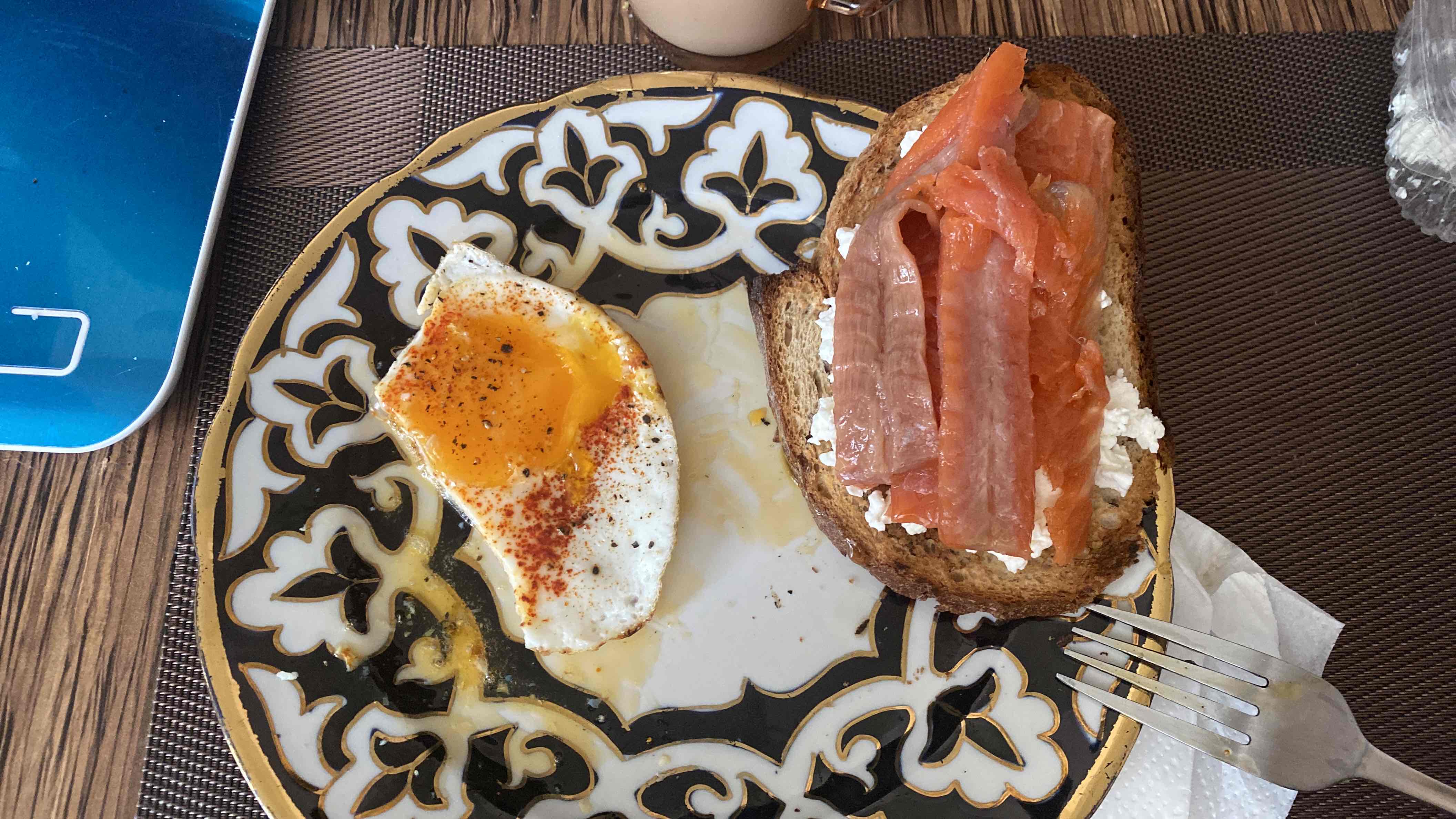 A nutritious meal consisting of two fried eggs, smoked salmon on bread with cottage cheese, providing a balanced mix of protein, fats, and carbs.