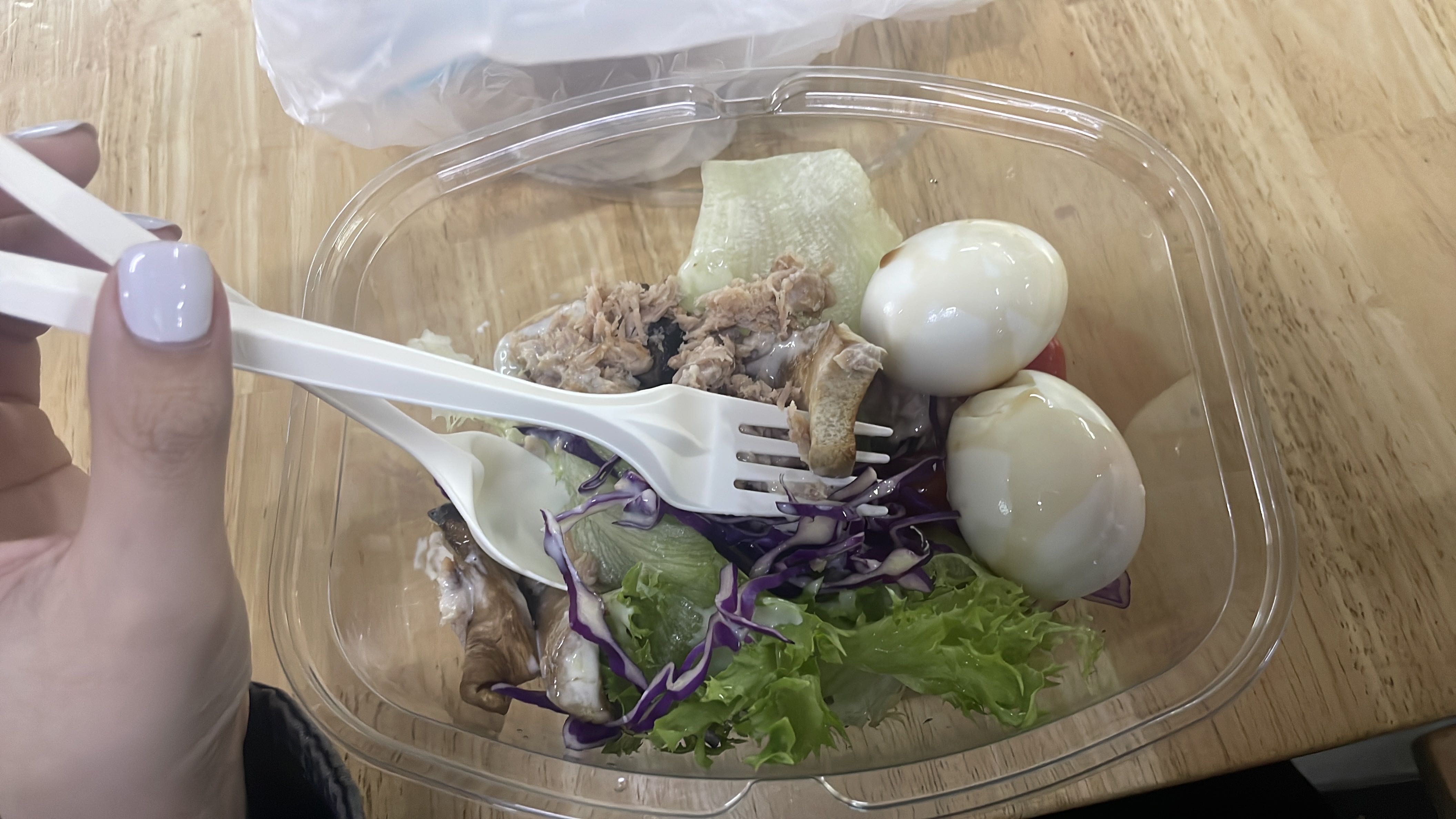 A healthy salad containing boiled eggs, lettuce, purple cabbage, grilled chicken, and salad dressing.