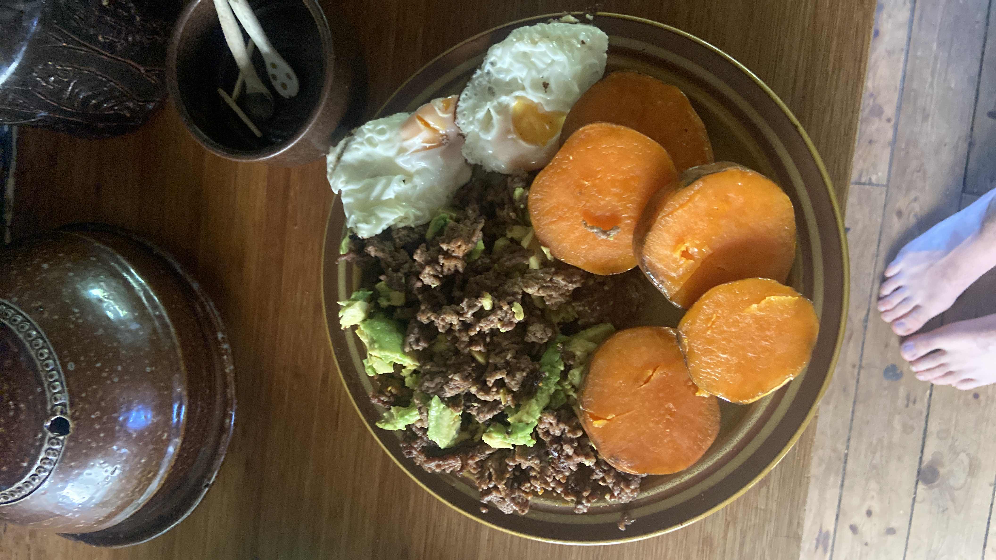 A balanced meal consisting of sweet potato slices, ground beef, avocado, and fried eggs, providing a good mix of protein, carbs, and healthy fats.