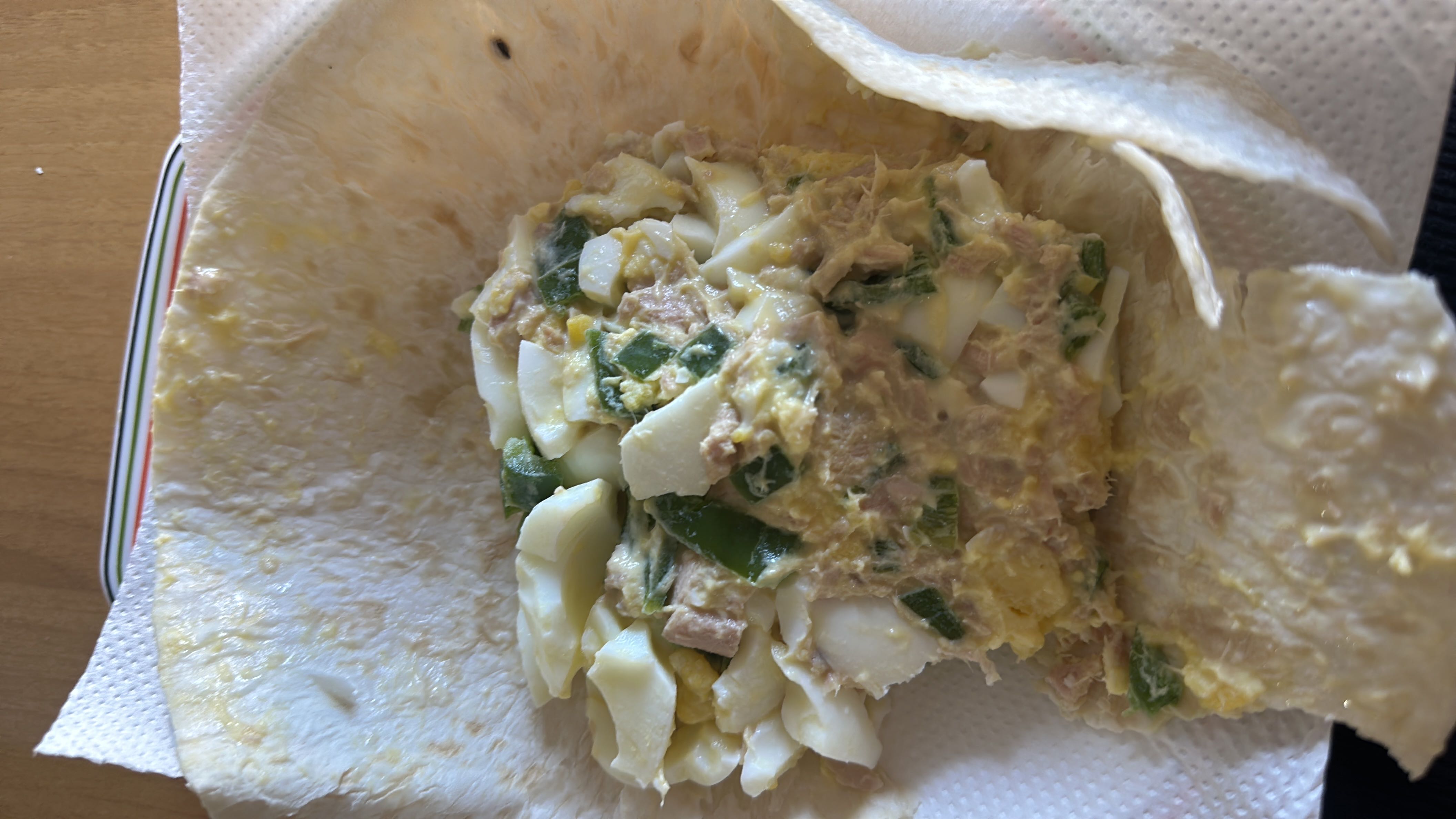 A 100% blé wrap filled with tuna, two boiled eggs, green pepper, and a teaspoon of fresh cheese.