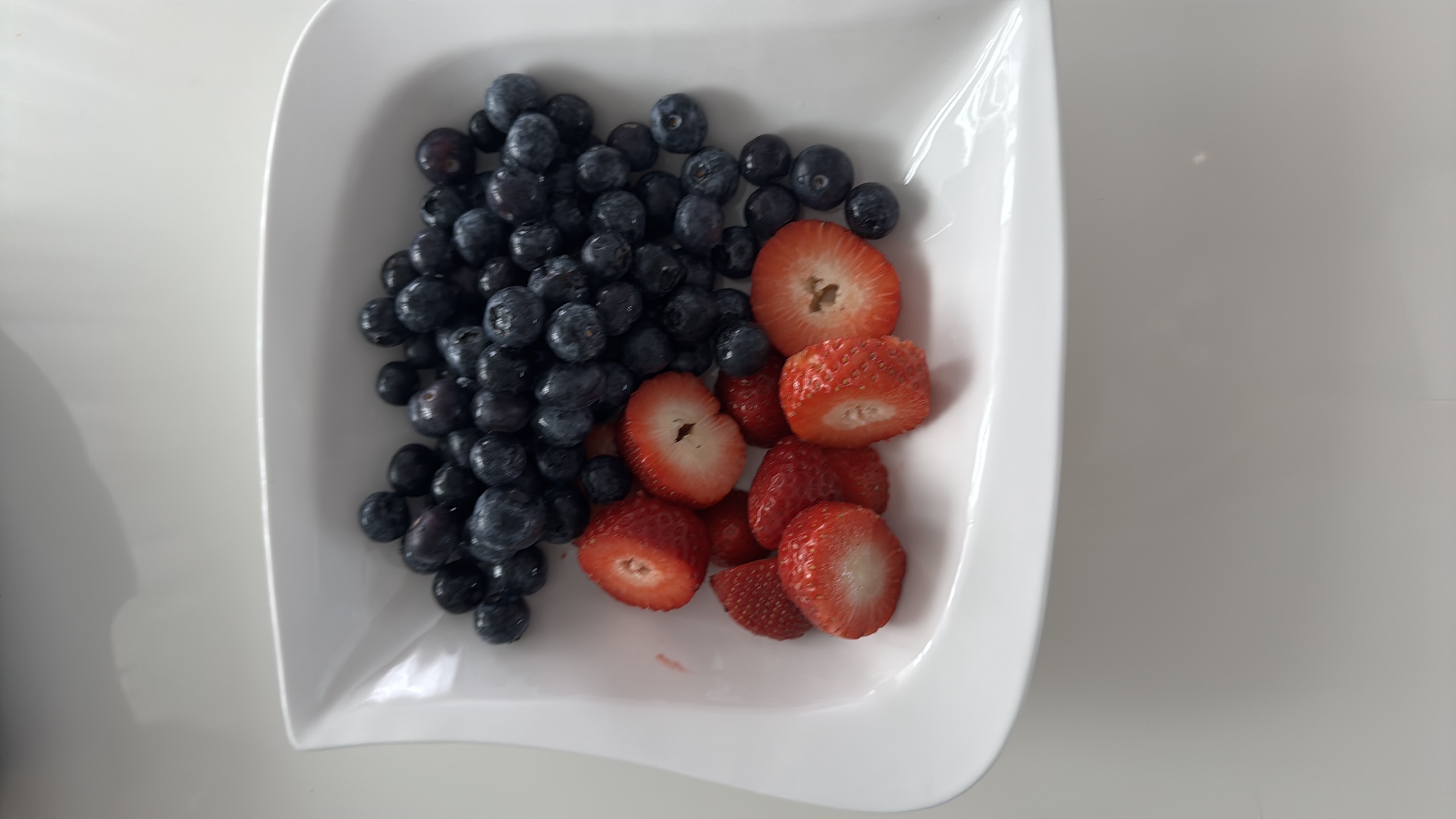 A bowl of fresh blueberries and strawberries, providing a low-calorie, nutrient-rich snack high in antioxidants and vitamins.