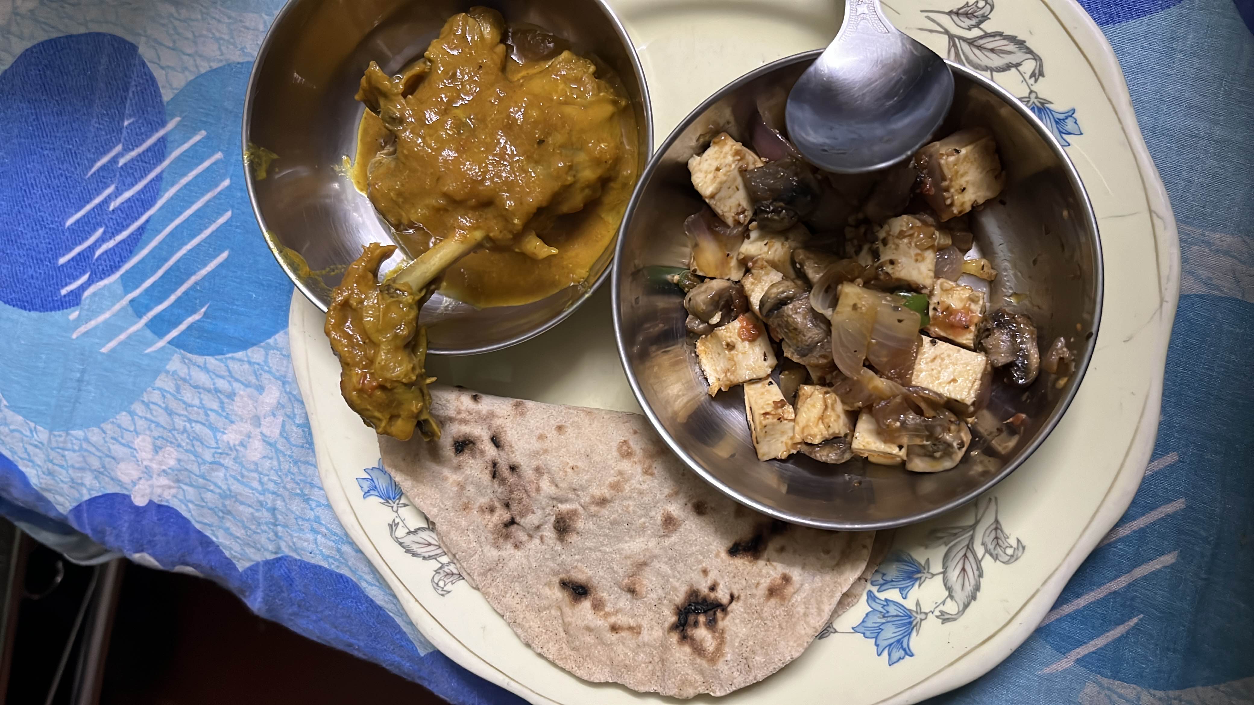 A balanced meal consisting of chapati, paneer and mushroom curry, and chicken curry, providing a good mix of protein, carbs, and fats.