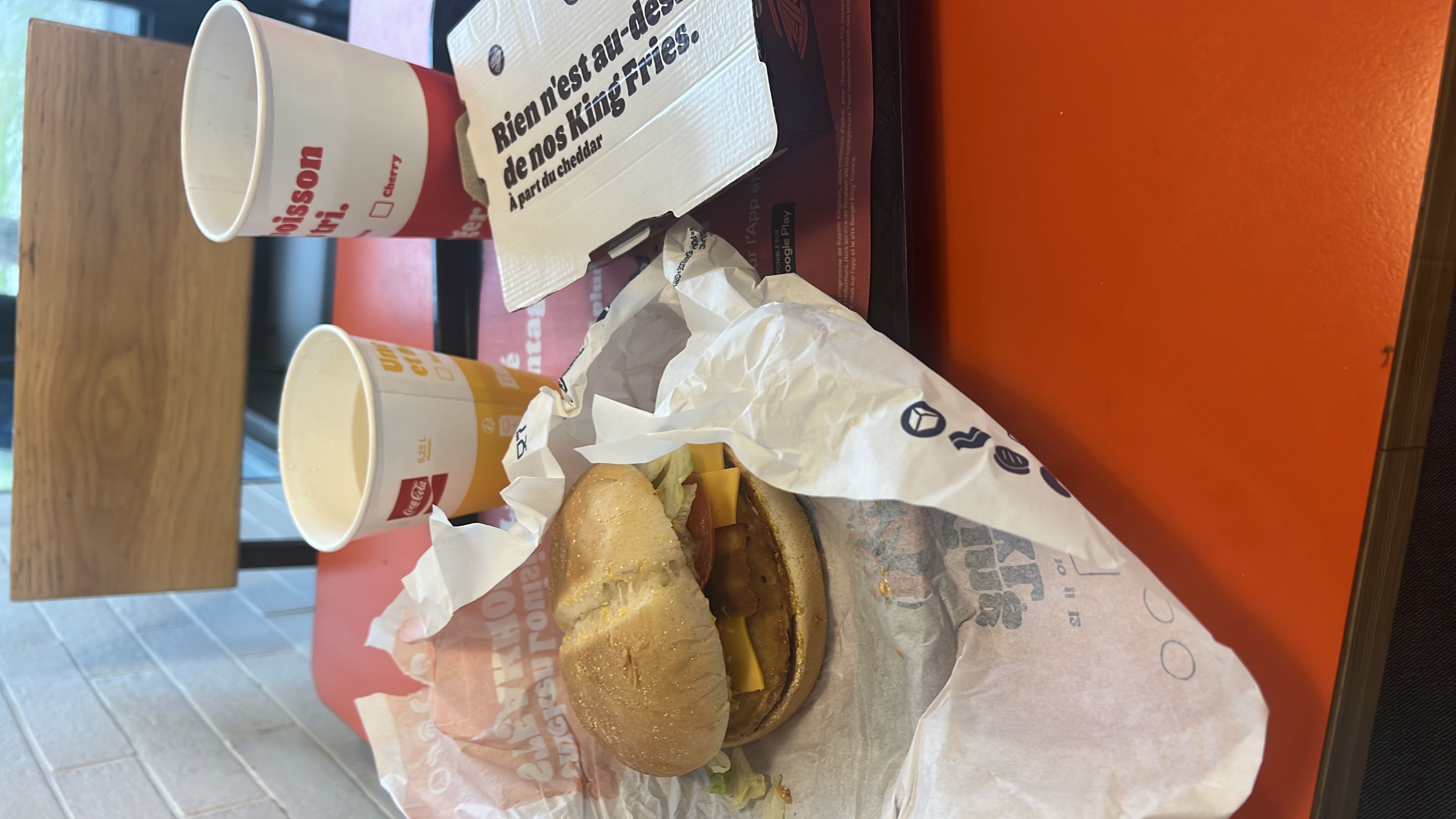 A fast-food meal consisting of a chicken burger with cheese, lettuce, and tomato, accompanied by fries and a soft drink.