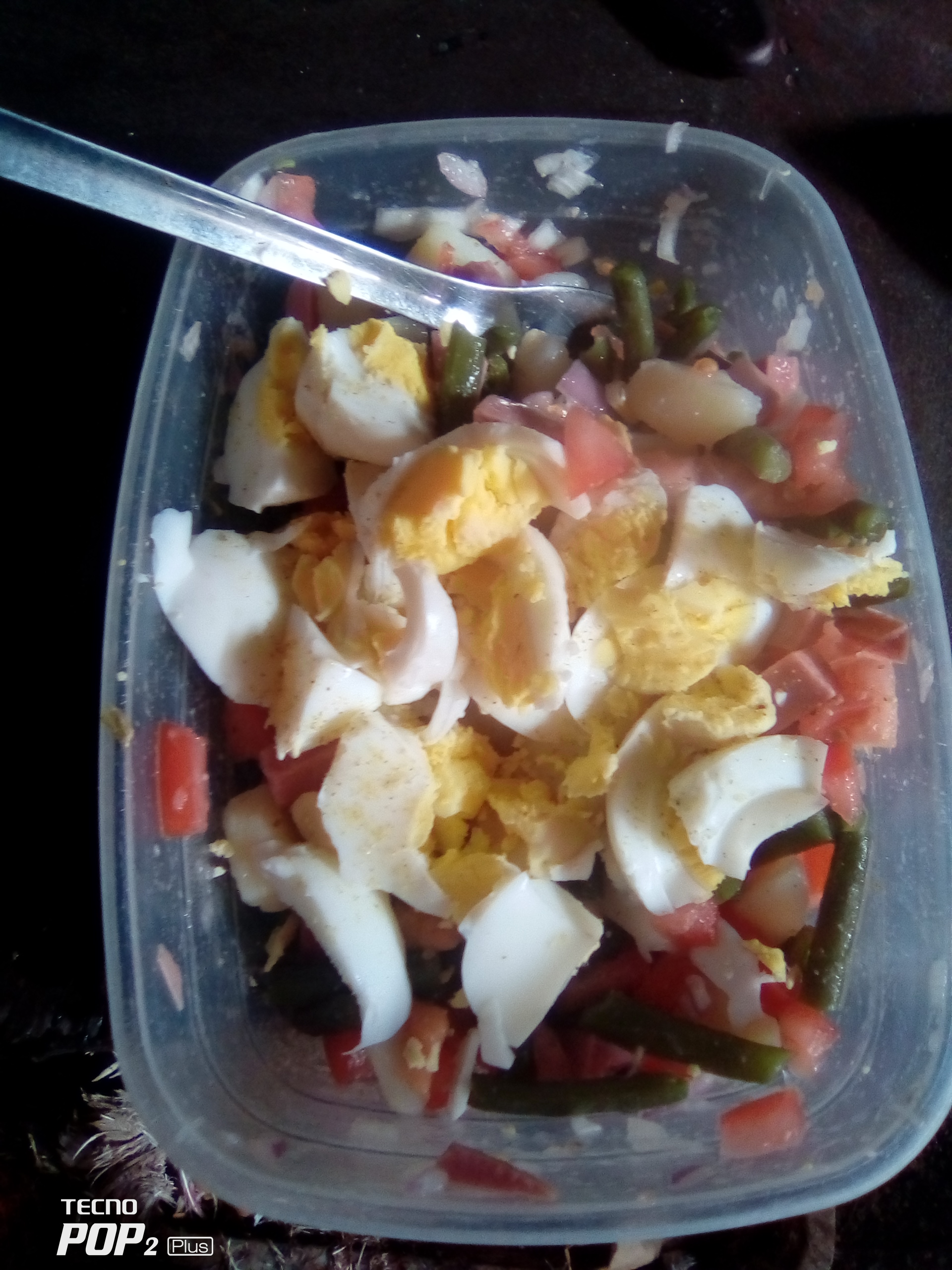 A healthy salad containing boiled eggs, green beans, tomatoes, and onions, providing a balanced mix of protein, carbs, and fats.