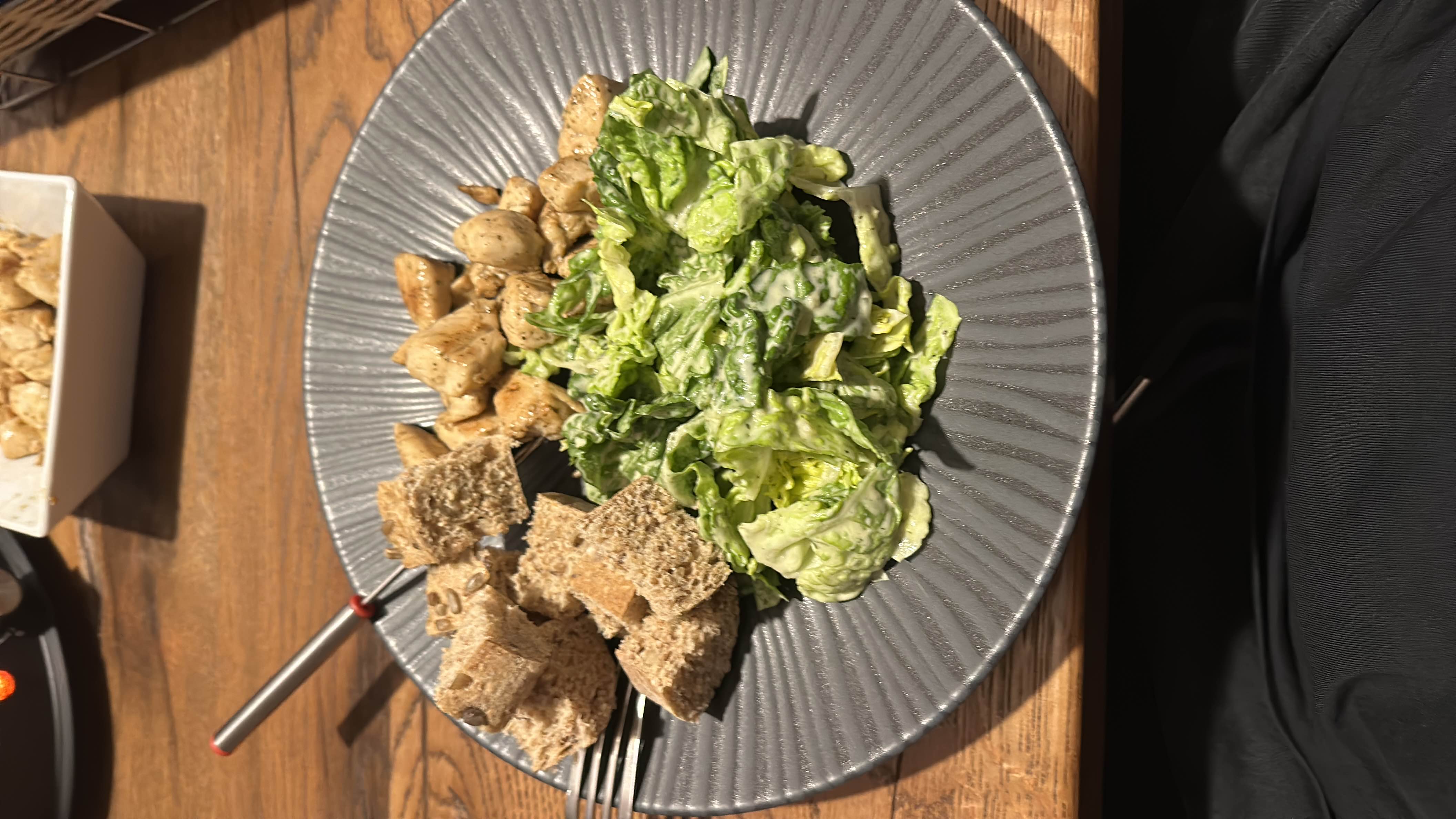 A balanced meal consisting of grilled chicken, lettuce salad with dressing, and whole grain bread.