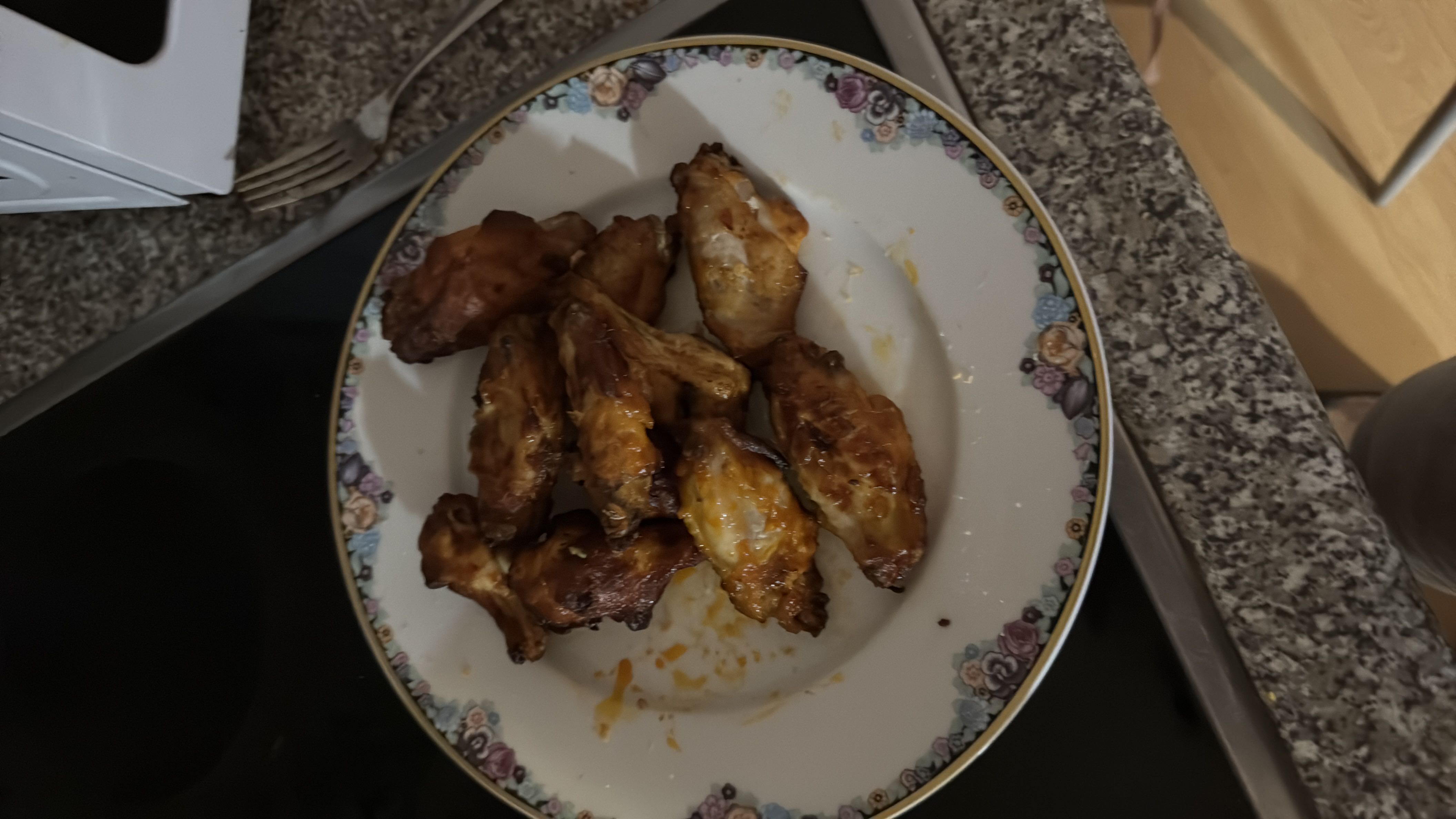 A plate of cooked chicken wings, likely seasoned and baked or fried, providing a high-protein and moderate-fat meal.