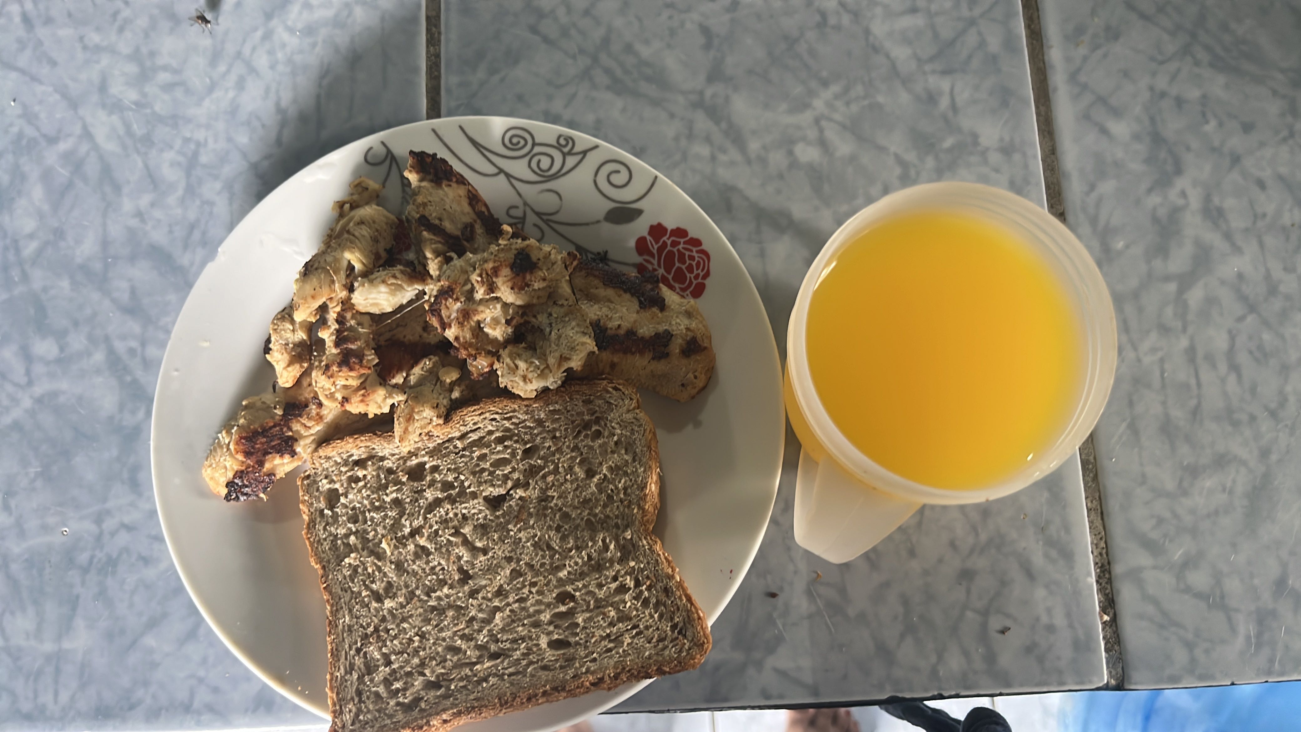 A meal consisting of whole grain bread, grilled chicken, and a cup of orange juice, providing a balanced mix of protein, carbs, and fats.