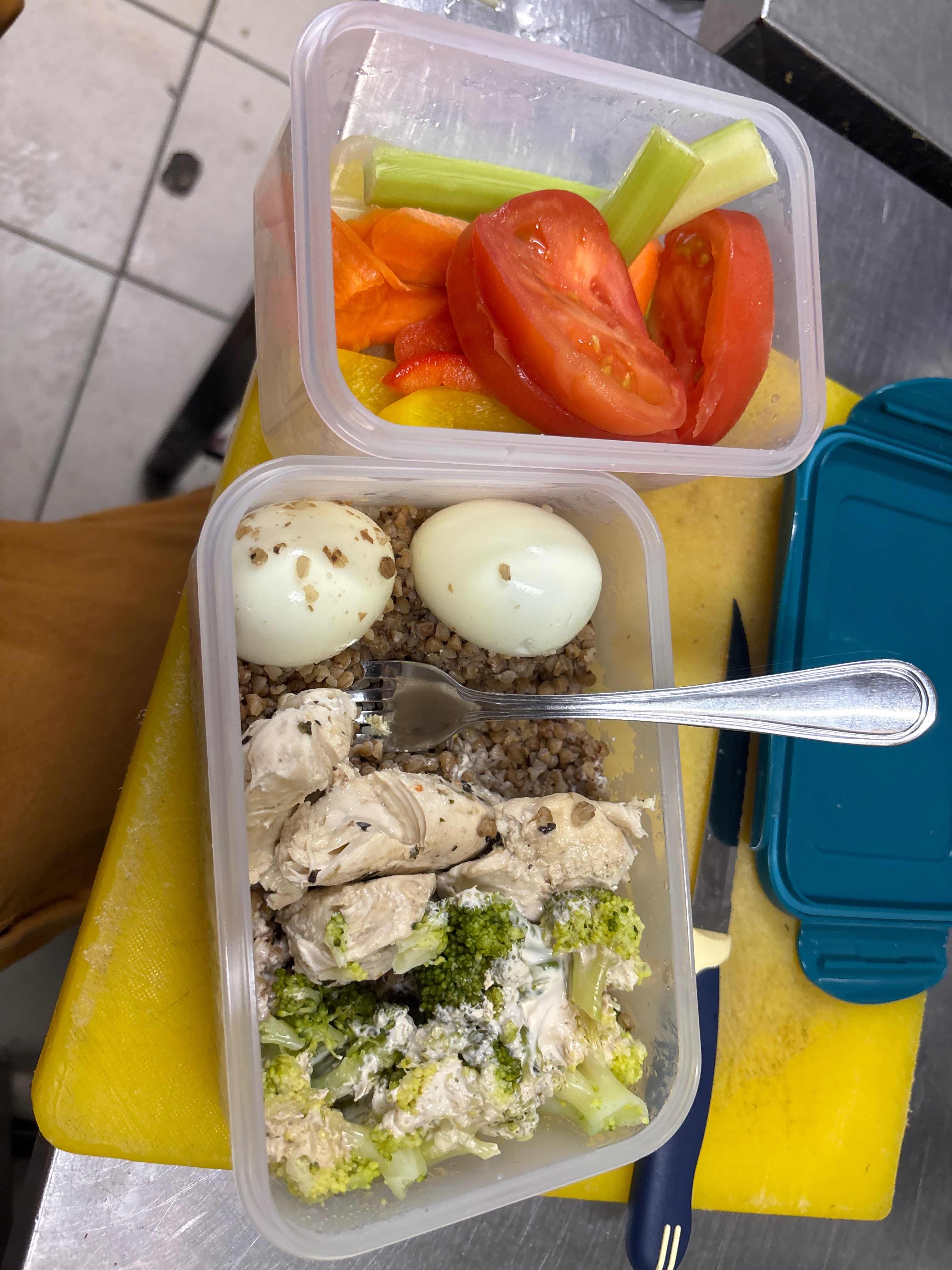 A balanced meal consisting of chicken breast, broccoli, buckwheat, boiled eggs, and raw vegetables, providing a good mix of protein, carbs, and fats.