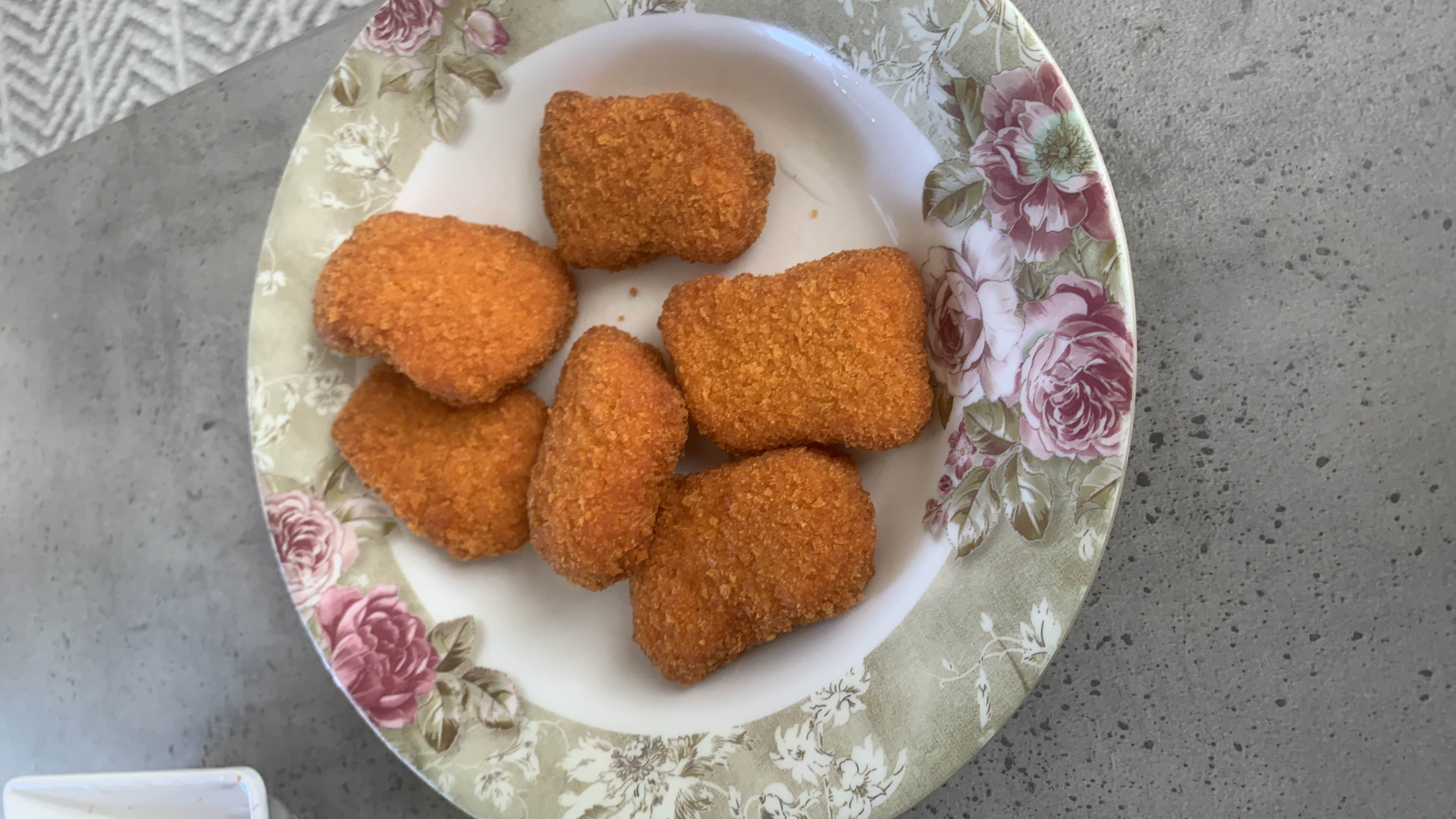A plate of breaded and fried chicken nuggets, typically high in calories, protein, and fats.