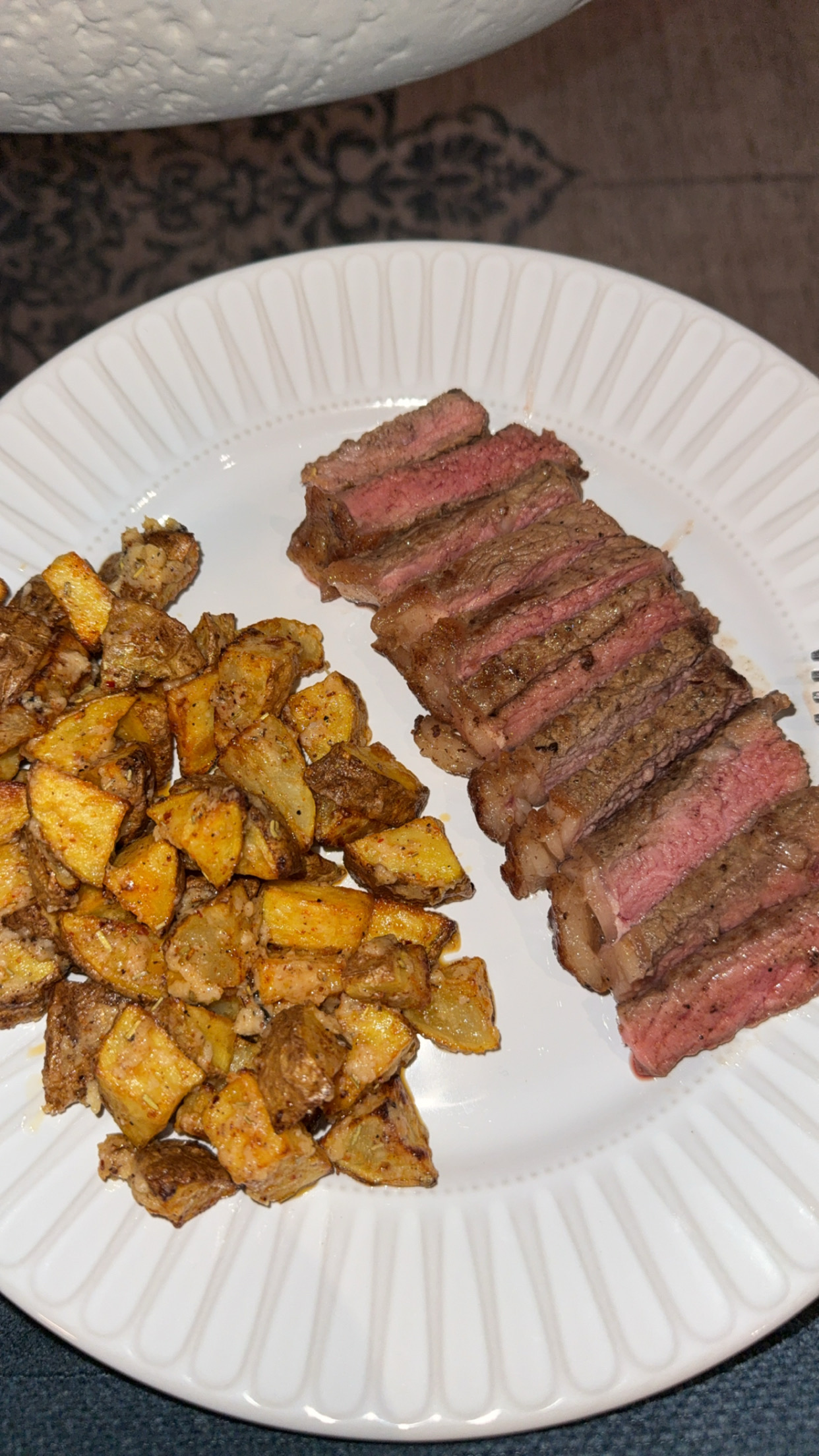 A plate featuring sliced steak and seasoned roasted potatoes, providing a balanced mix of protein, carbs, and fats.