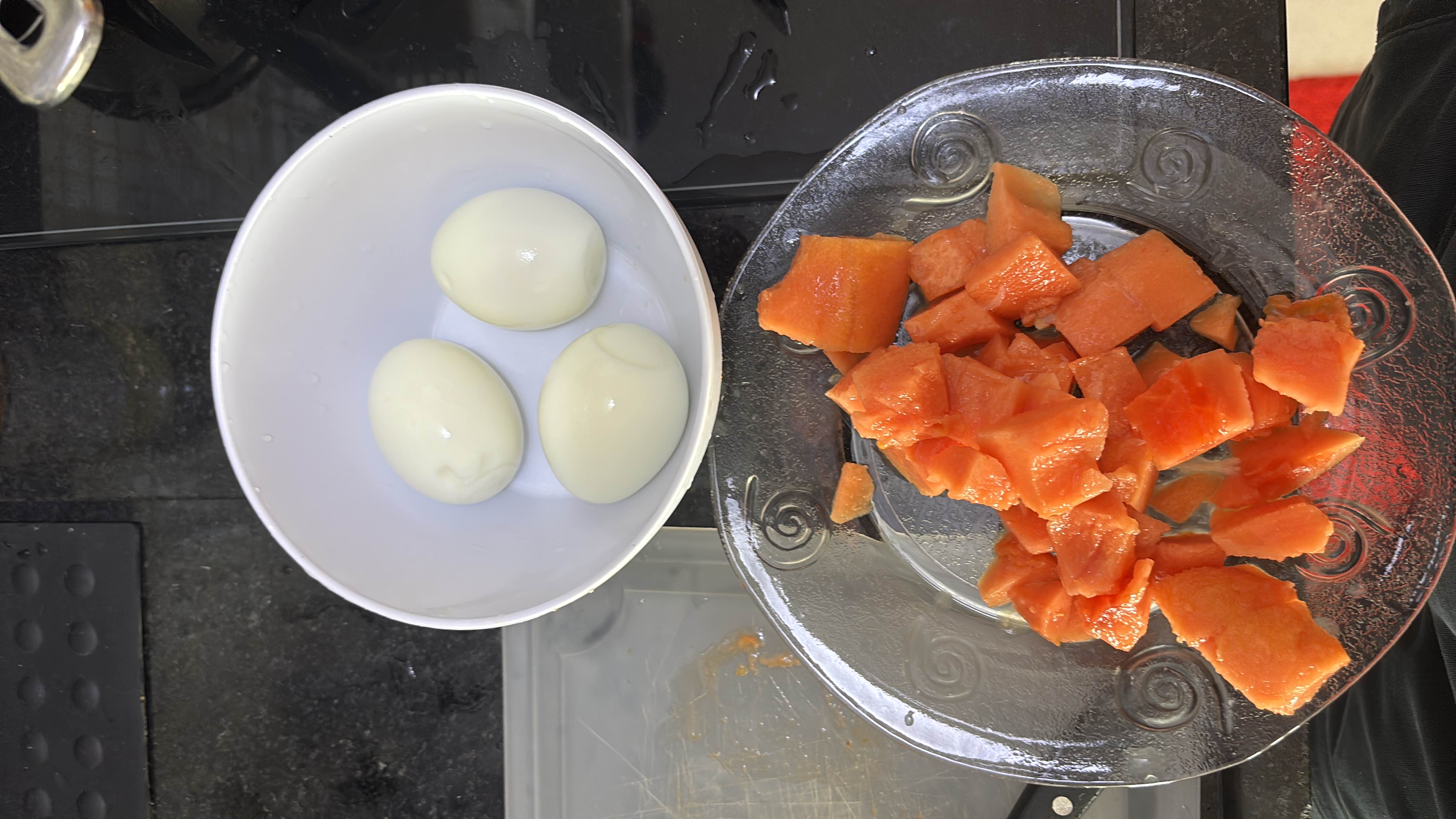 A healthy meal consisting of three boiled eggs and a serving of diced papaya, providing a balanced mix of protein, carbs, and fats.