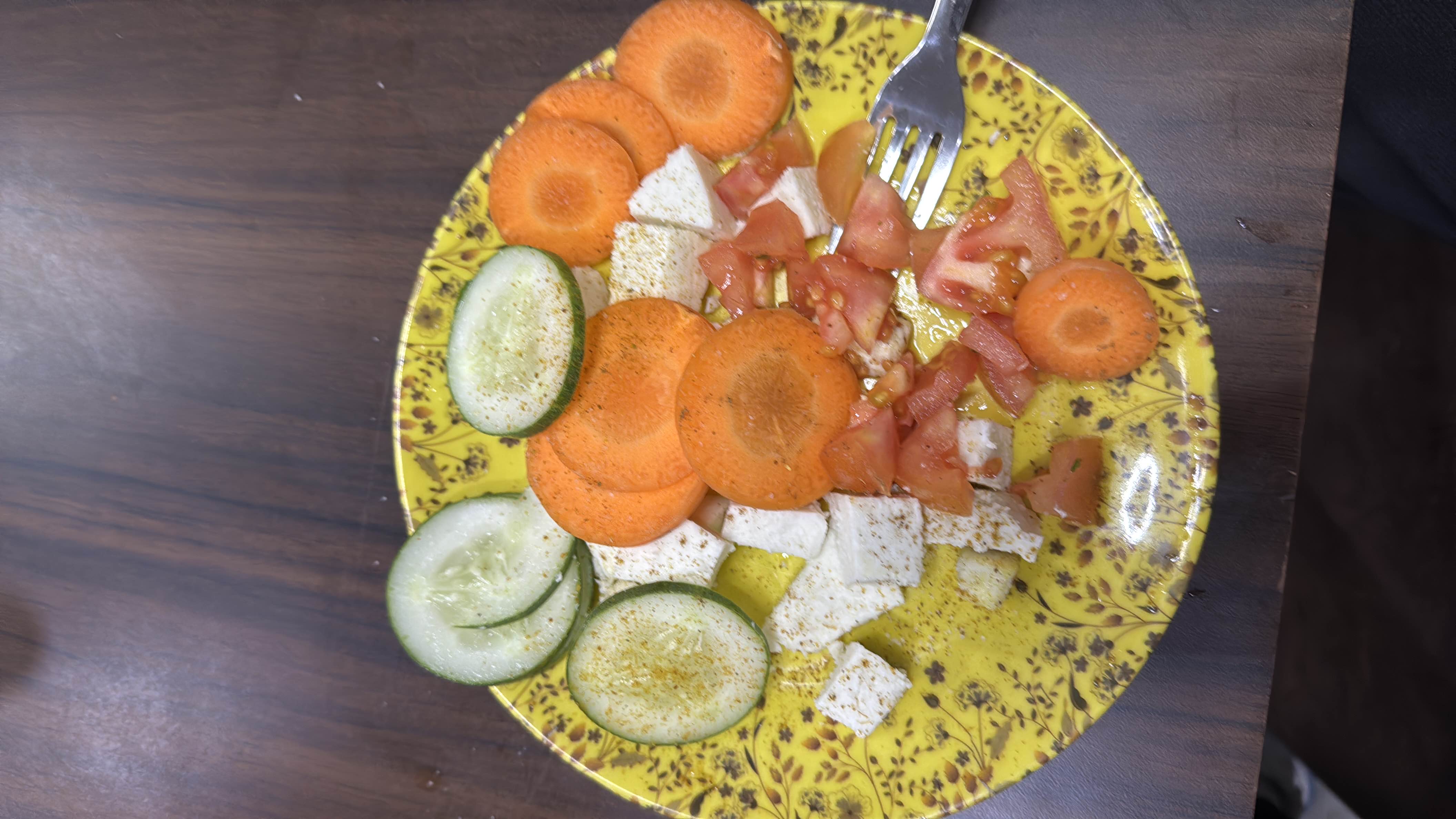 A healthy salad consisting of cucumber, carrot, tomato, and paneer, lightly seasoned.
