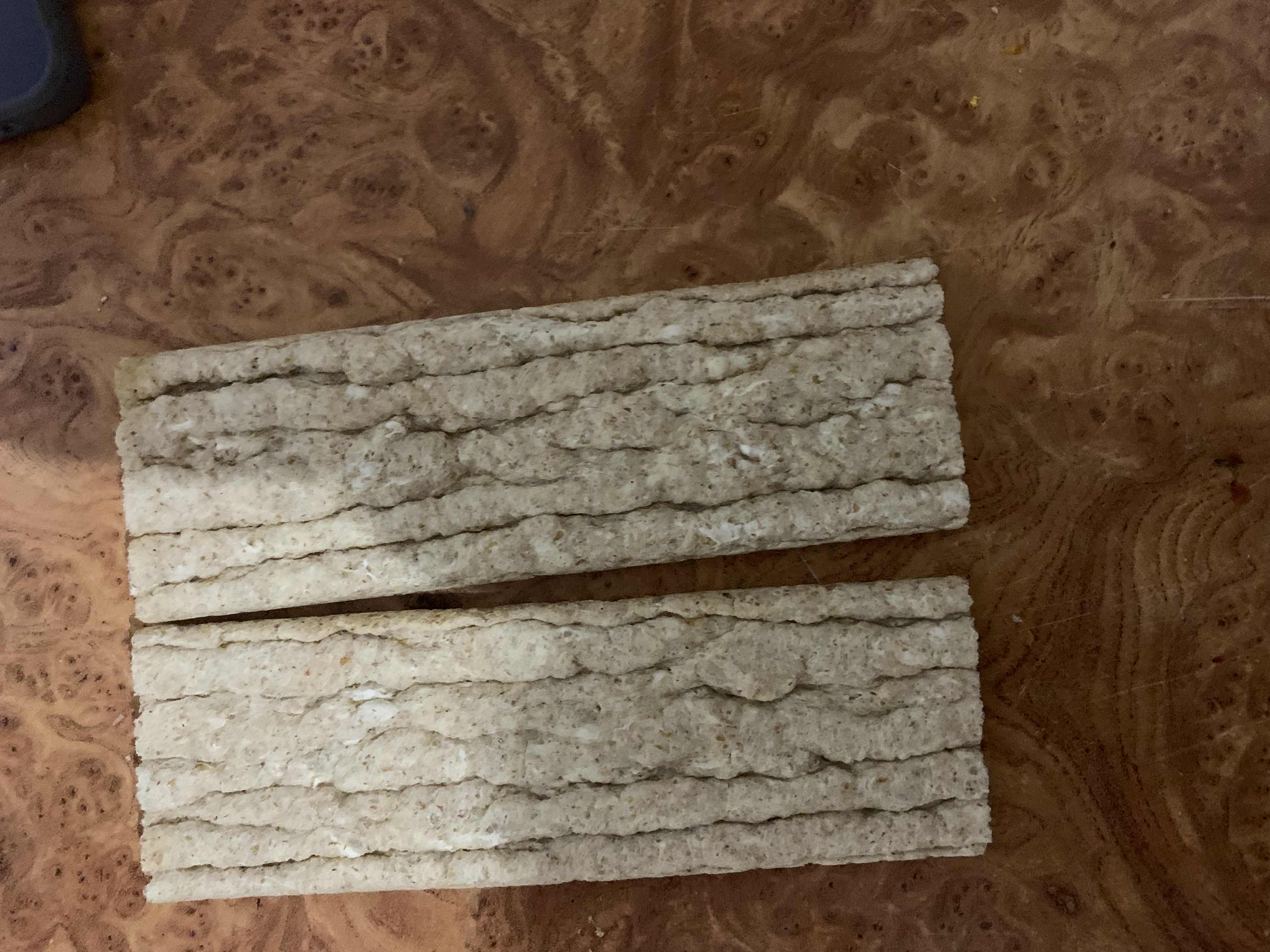 The image shows two pieces of whole grain crispbread, a low-calorie snack high in carbohydrates and fiber, with minimal fats and moderate protein content.