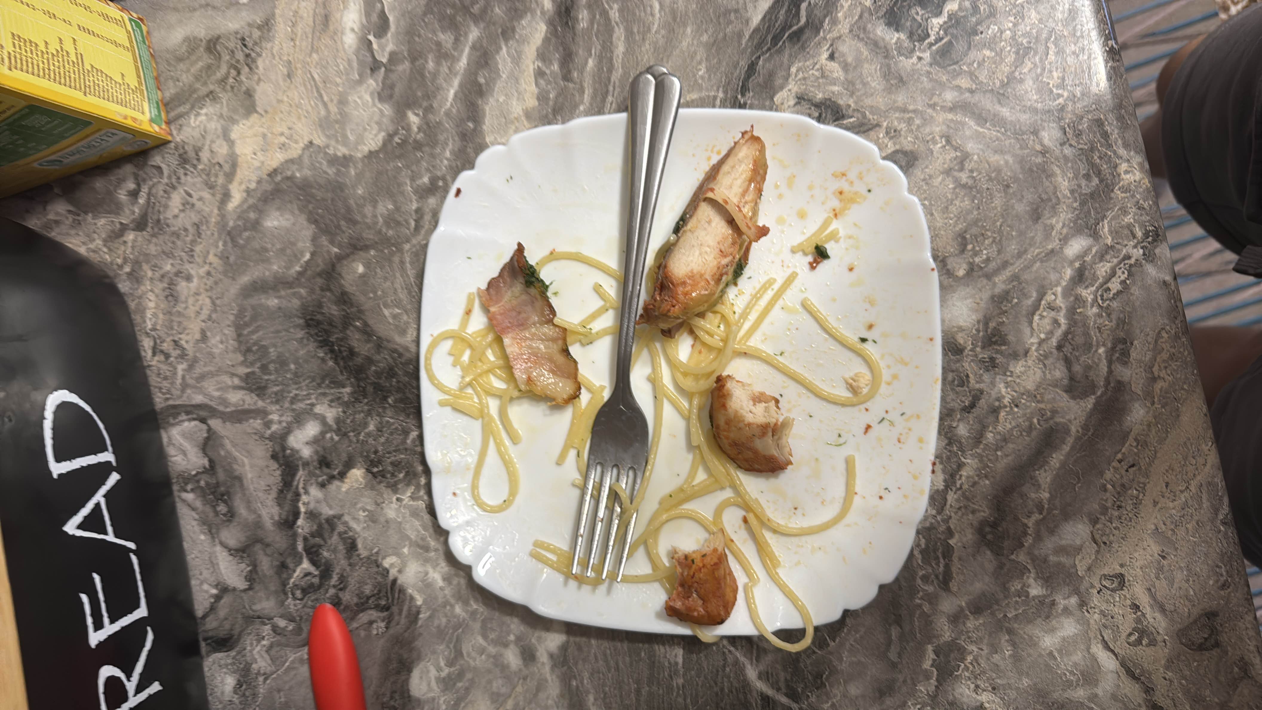 A plate containing leftover spaghetti and grilled chicken, providing a balanced mix of protein, carbs, and fats.