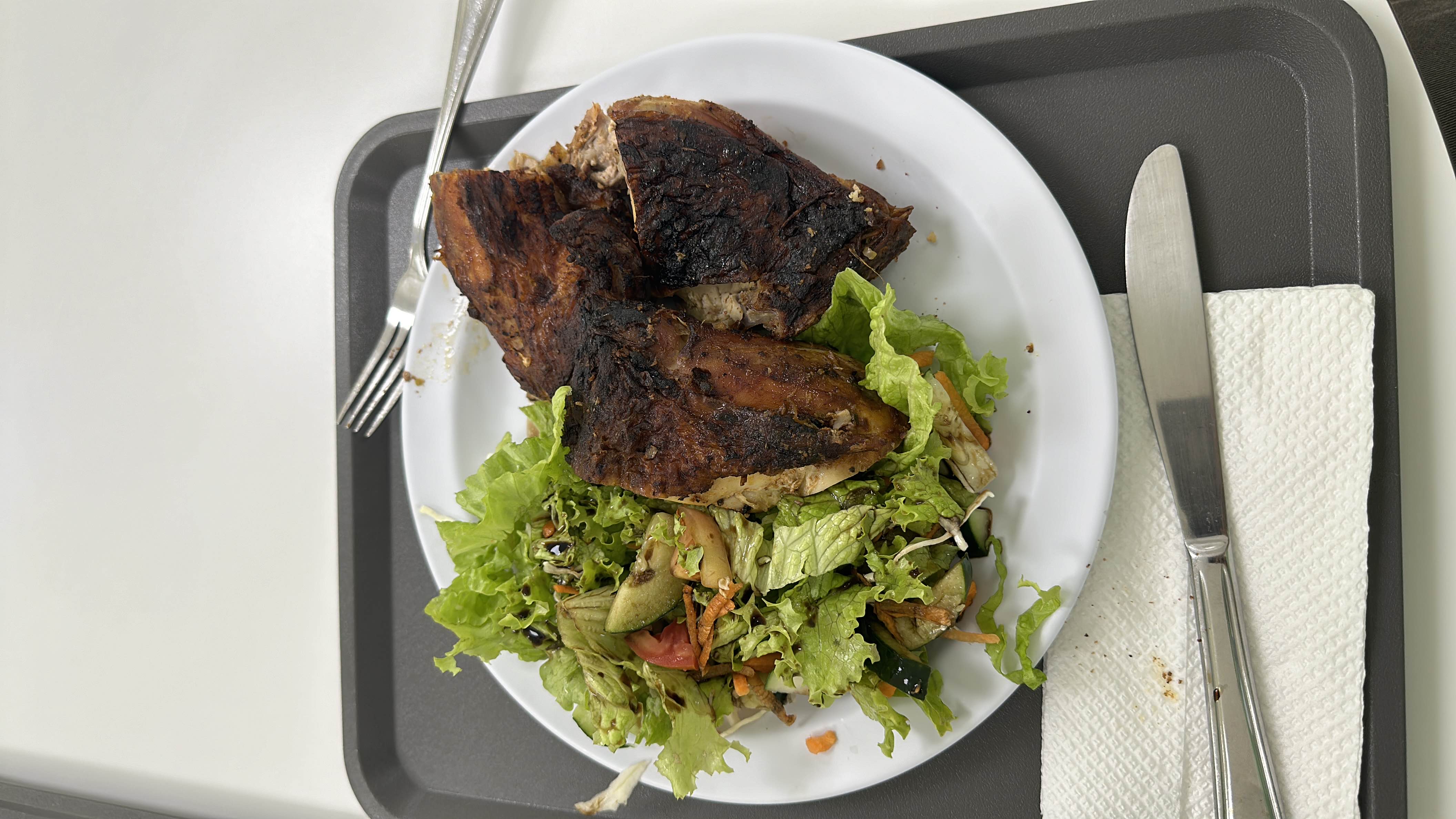 A plate of grilled chicken served with a fresh mixed salad and dressing, providing a balanced meal with moderate calories and a high protein content.