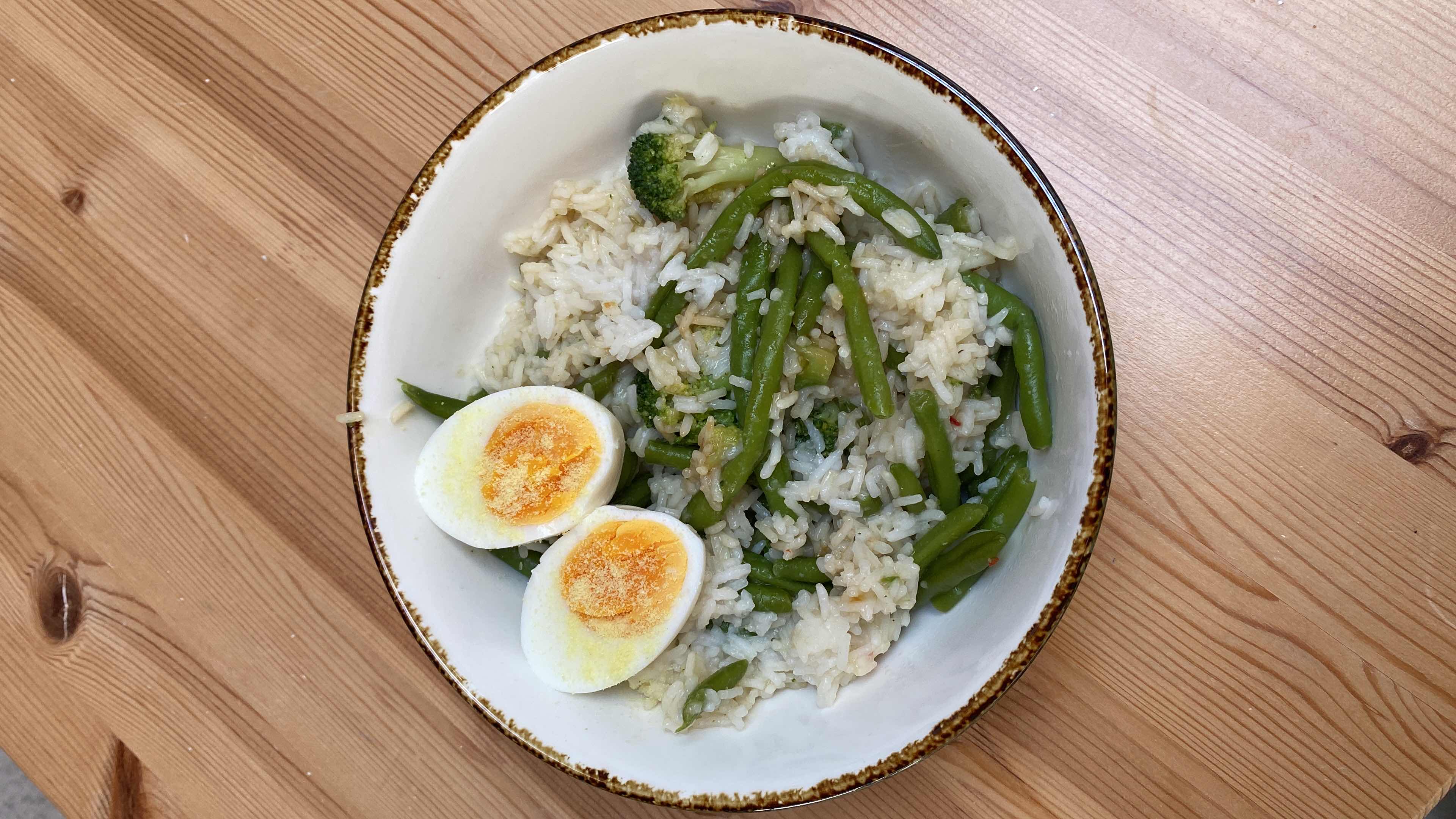 A nutritious dish consisting of rice, green beans, and a boiled egg, providing a balanced mix of protein, carbohydrates, and fats.