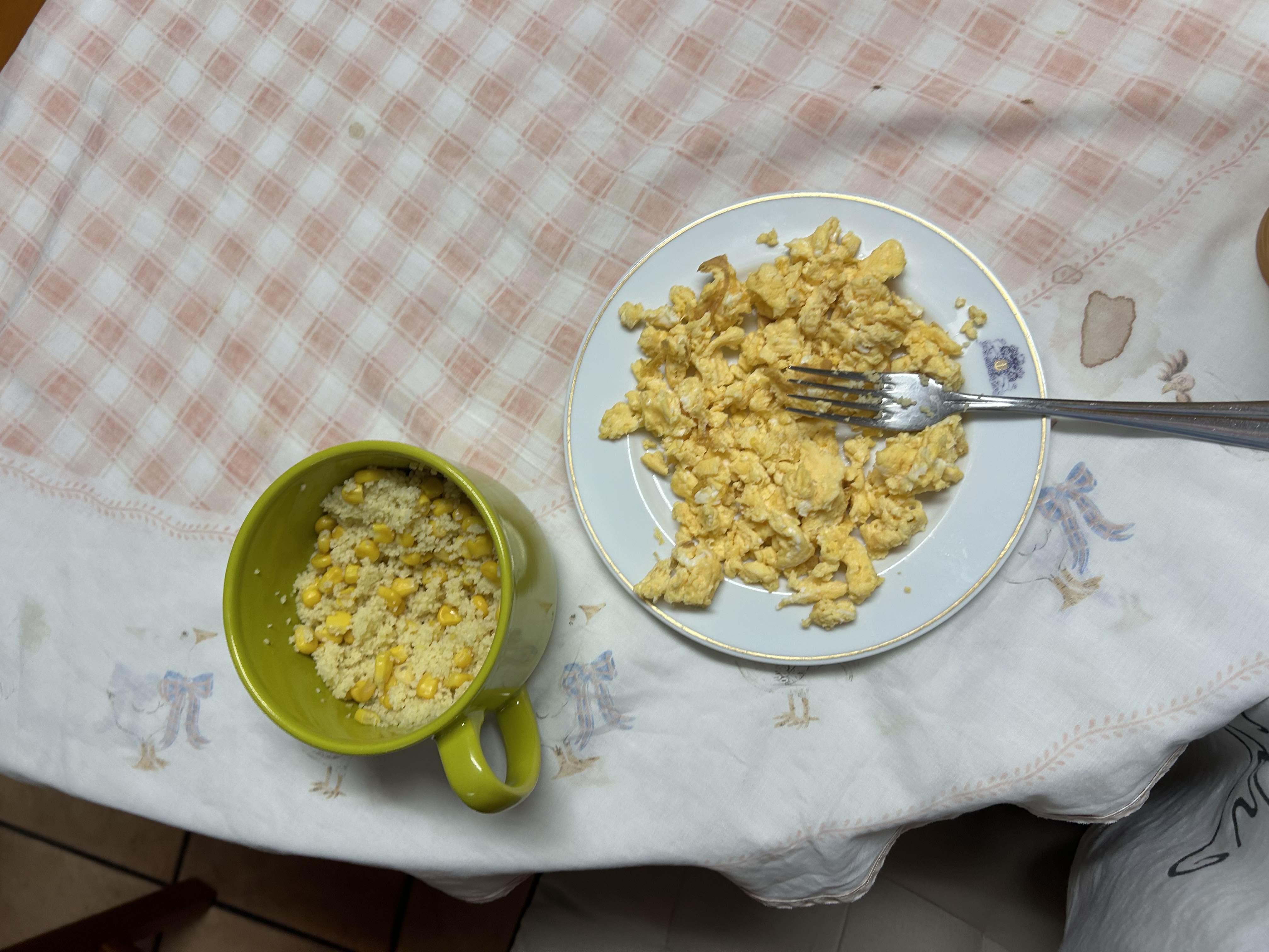A meal consisting of scrambled eggs and a side of couscous mixed with corn, providing a balanced mix of protein, carbs, and fats.