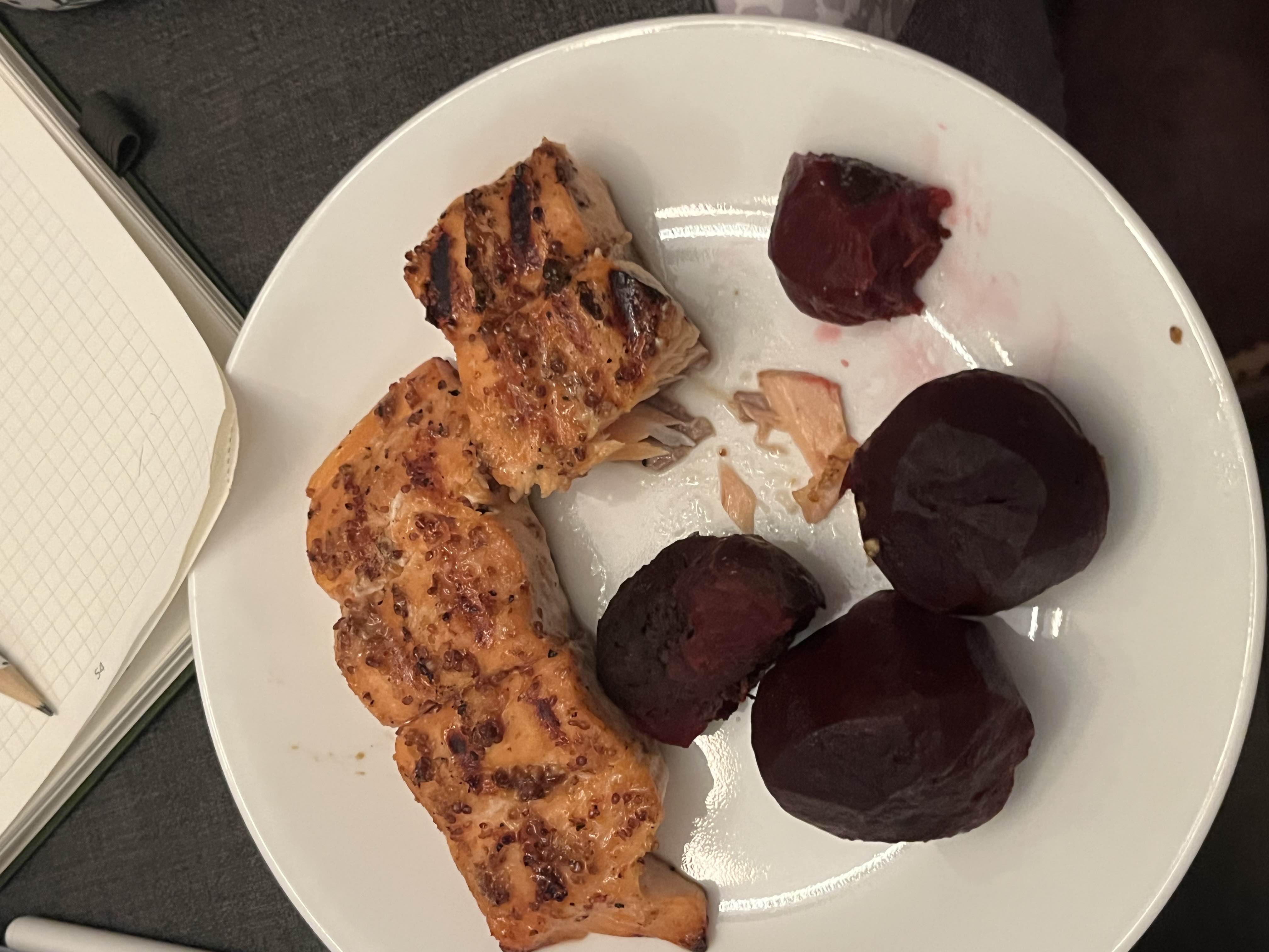 The image shows a plate with grilled salmon and boiled beets, providing a balanced meal rich in protein and nutrients.