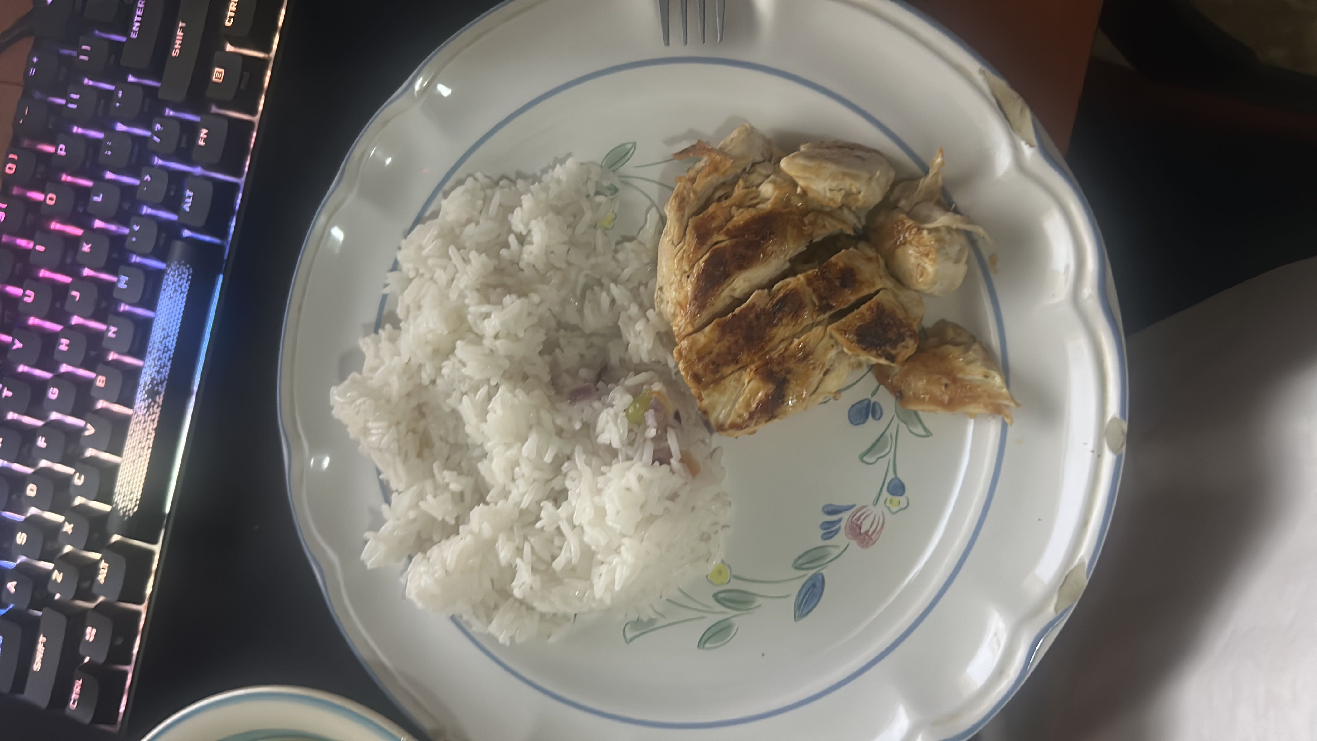 A plate containing white rice and grilled chicken, providing a balanced meal with moderate calories and protein.