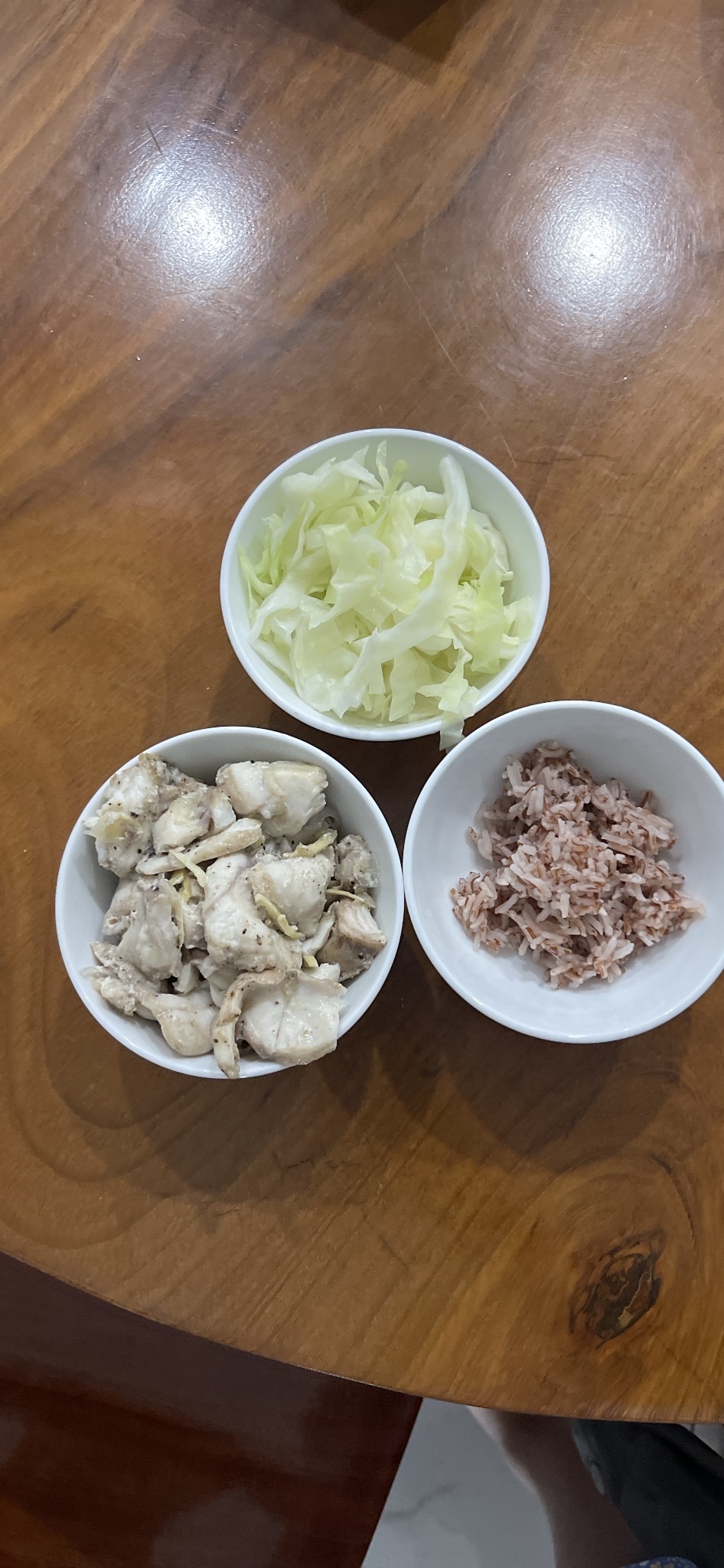 A balanced meal consisting of steamed cabbage, cooked chicken, and brown rice, providing a good mix of protein, carbs, and minimal fats.