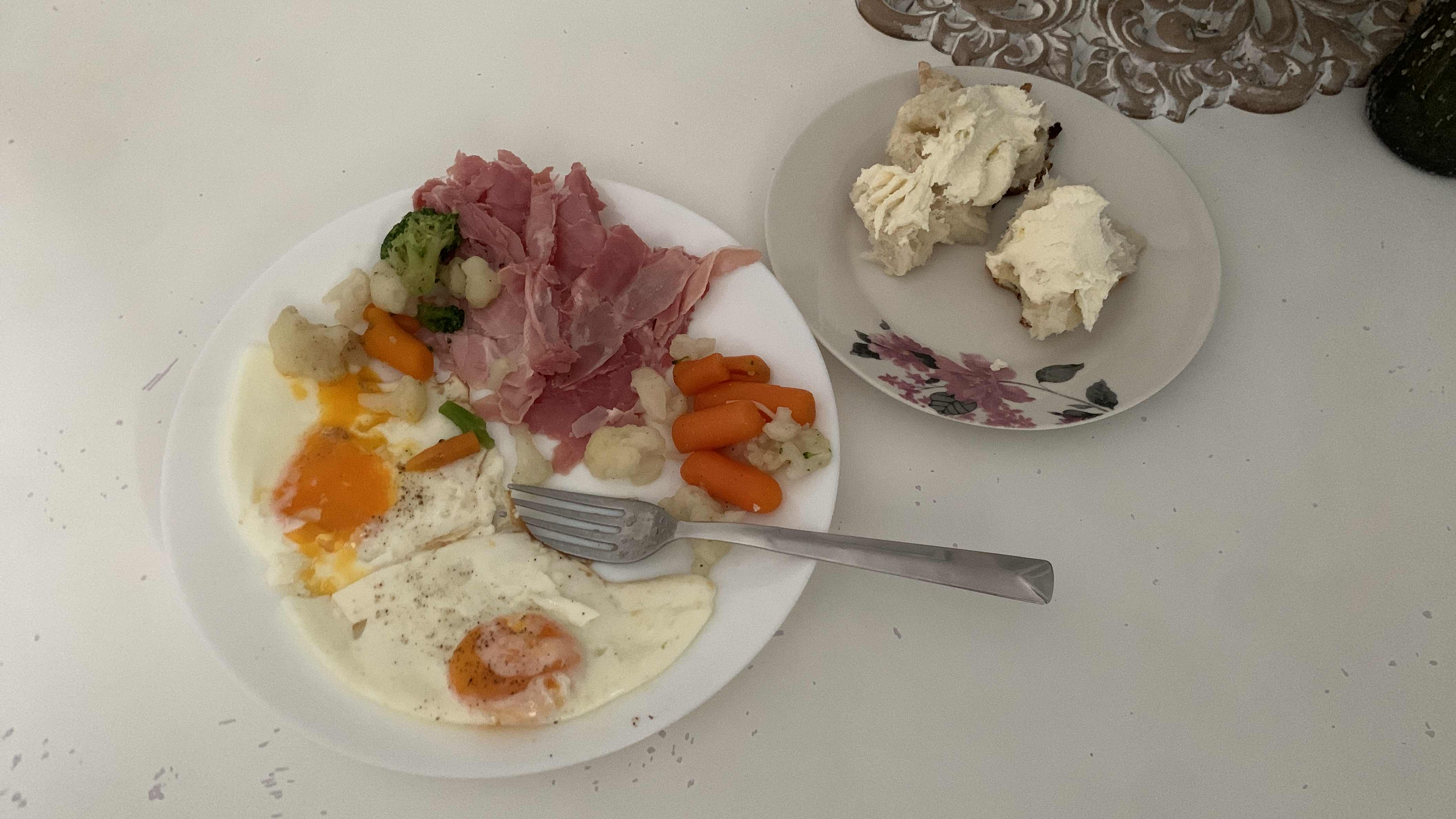 A balanced meal consisting of 3 eggs, ham, mixed vegetables, and bread with cream.