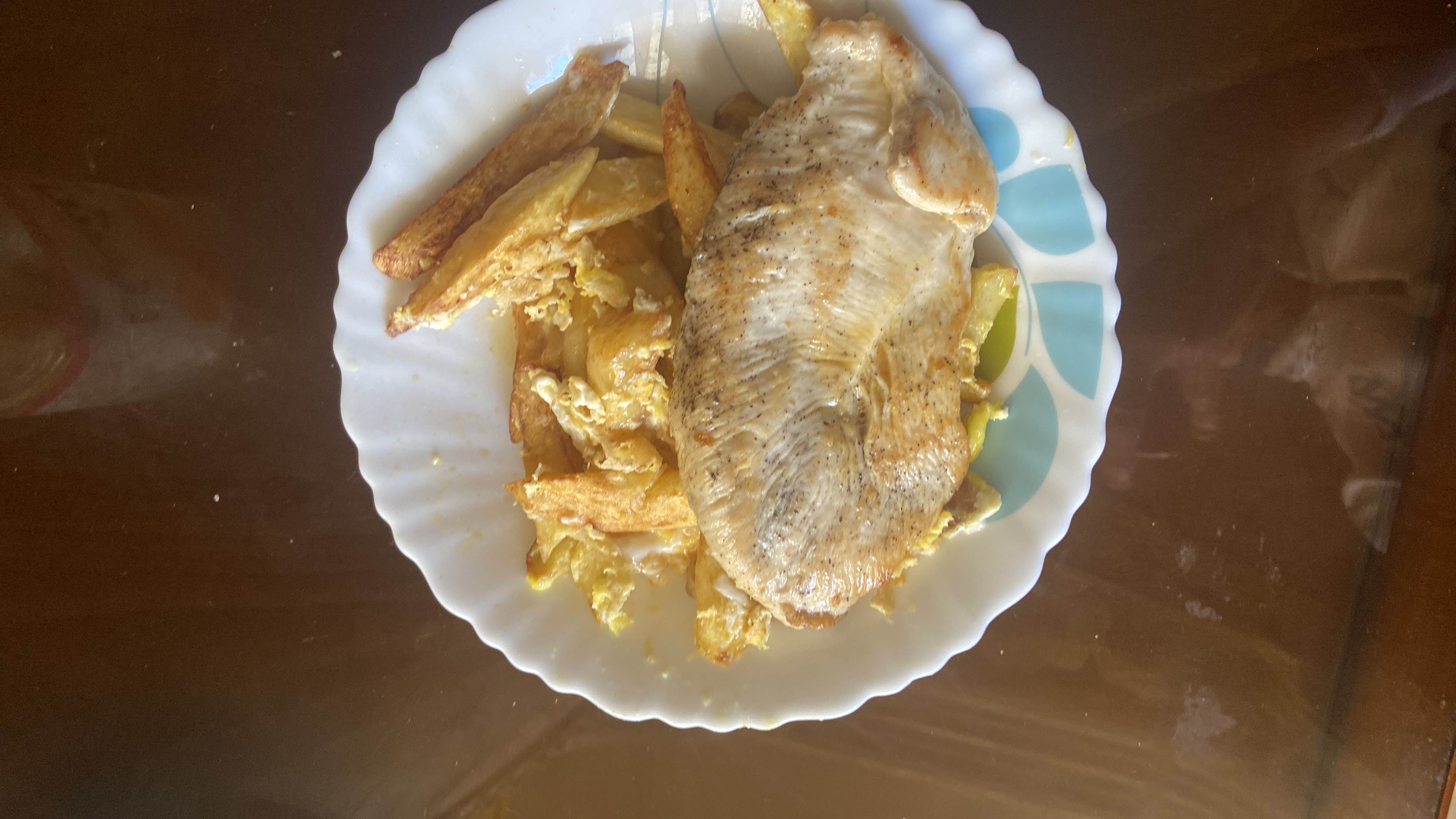 A plate containing grilled chicken breast, fried potatoes, and scrambled eggs, providing a balanced mix of protein, carbs, and fats.