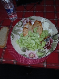 A balanced meal consisting of grilled chicken breast, fresh cucumber slices, a slice of bread, and cream cheese.