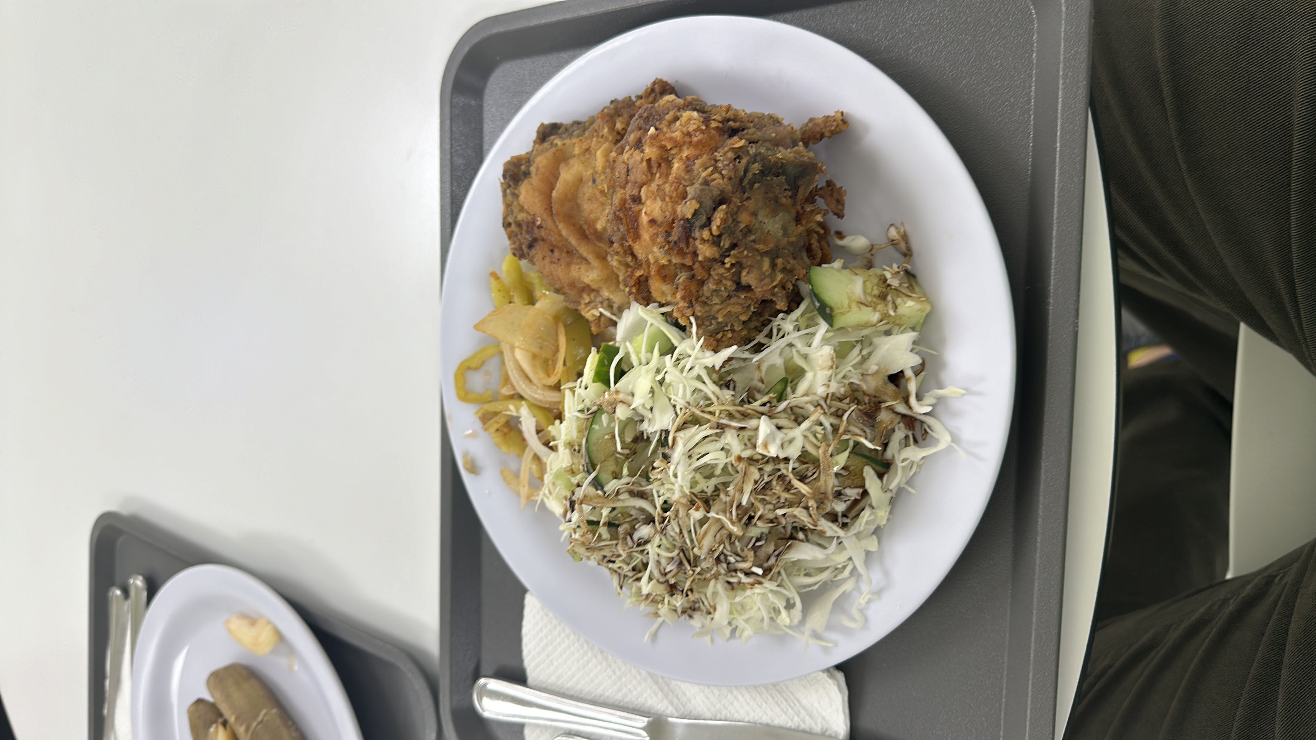 A meal consisting of fried chicken, cabbage salad with dressing, and cooked vegetables.