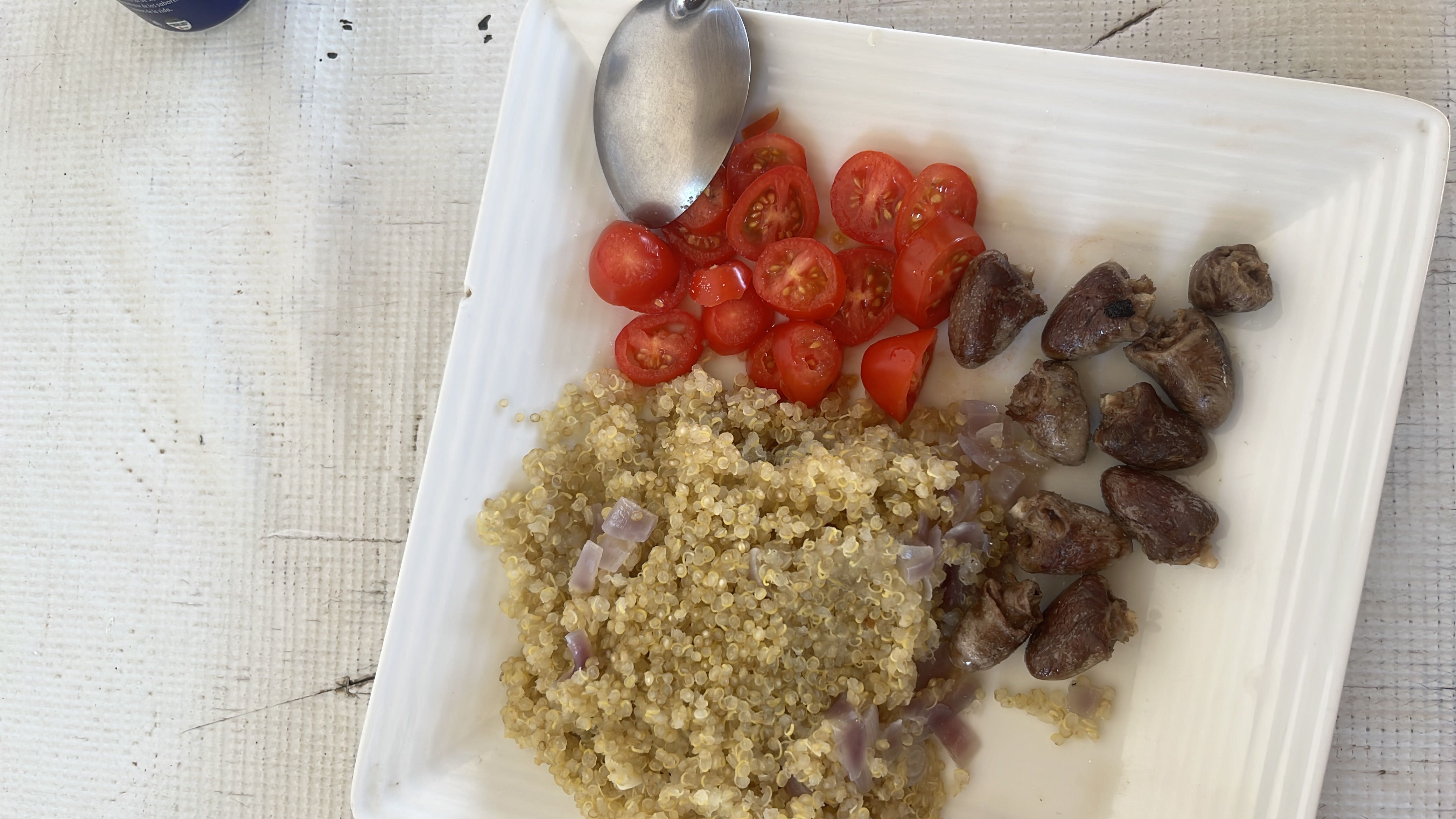 A balanced meal consisting of quinoa, cherry tomatoes, and chicken hearts, providing a good mix of protein, carbs, and fats.