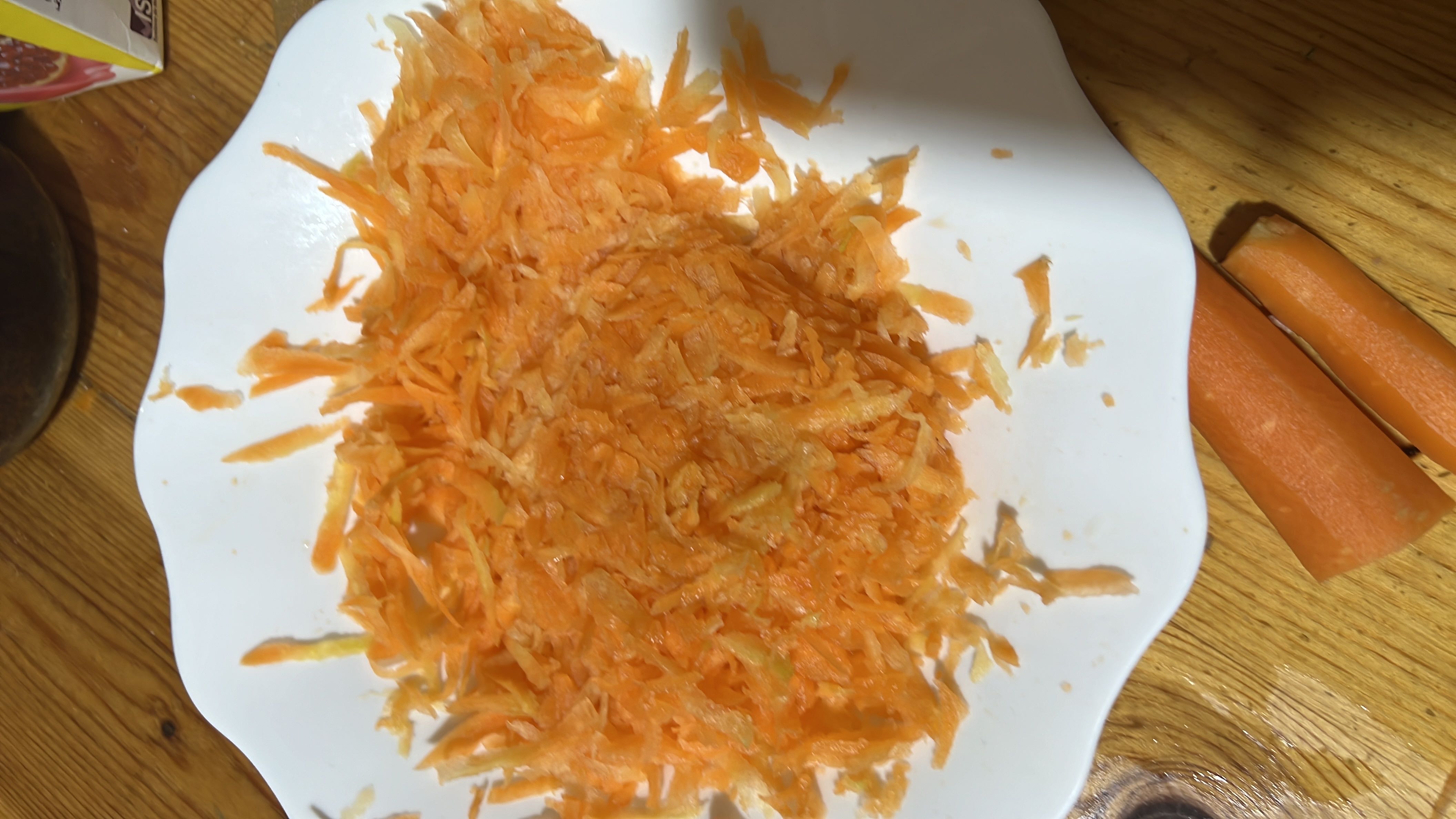 The image shows a plate of freshly grated carrots, which are low in calories and rich in nutrients.