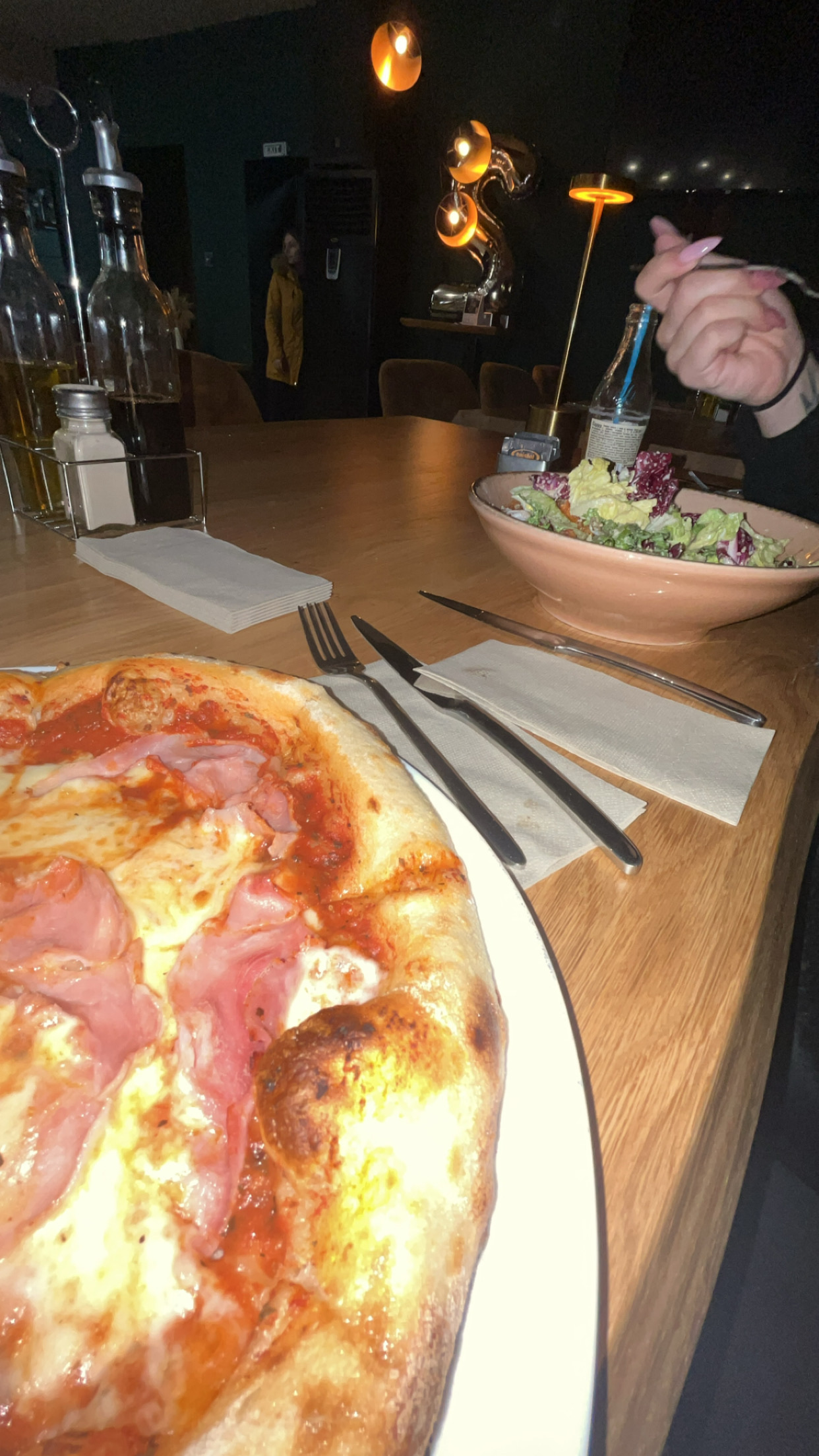 The image shows a meal consisting of a pizza with ham and cheese, and a side salad with lettuce and dressing.