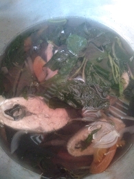 A nutritious fish soup with spinach and tomatoes, providing a balanced mix of protein, carbs, and fats.