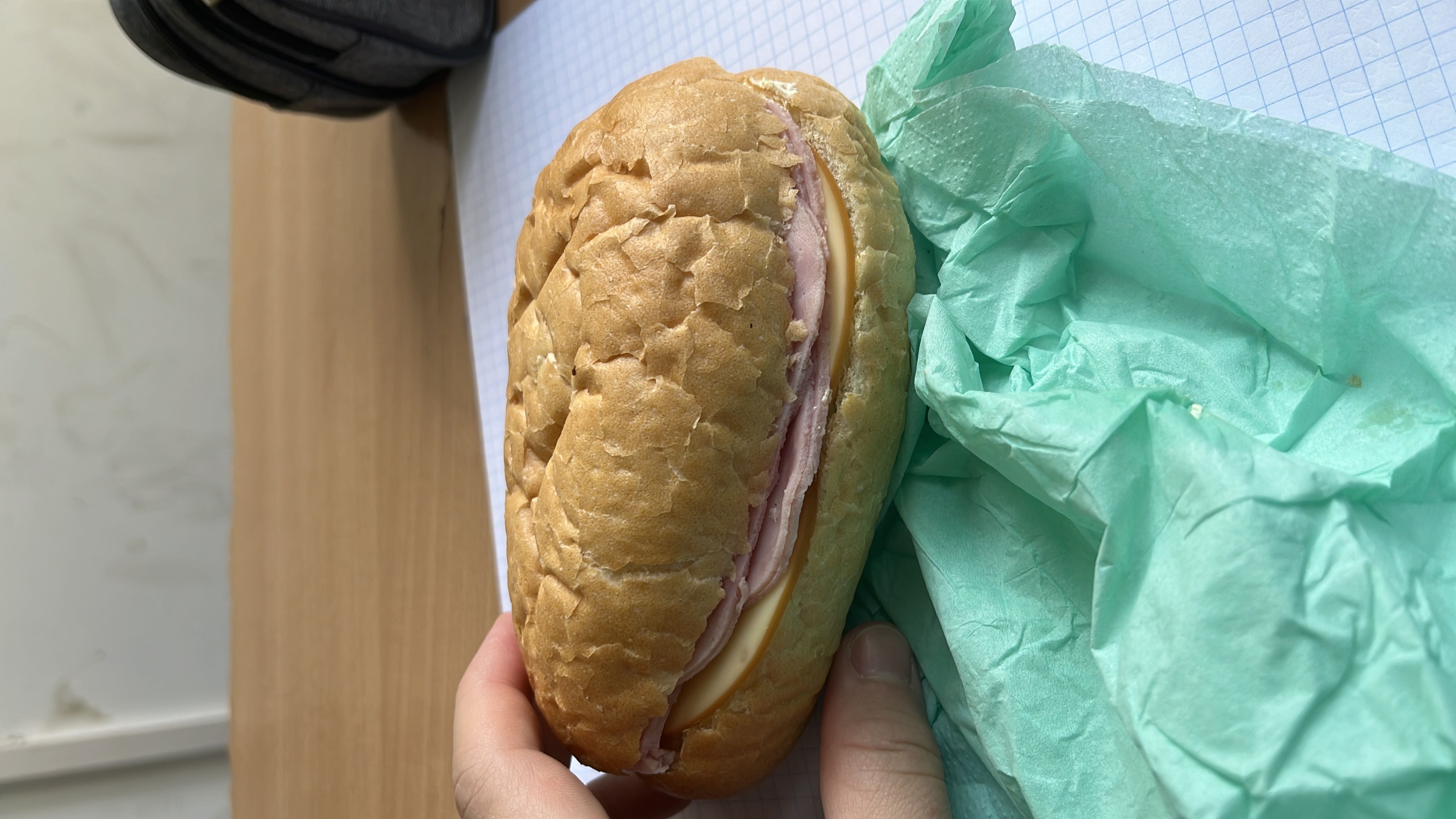 A ham and cheese sandwich on a bread roll, providing a balanced mix of protein, carbs, and fats.