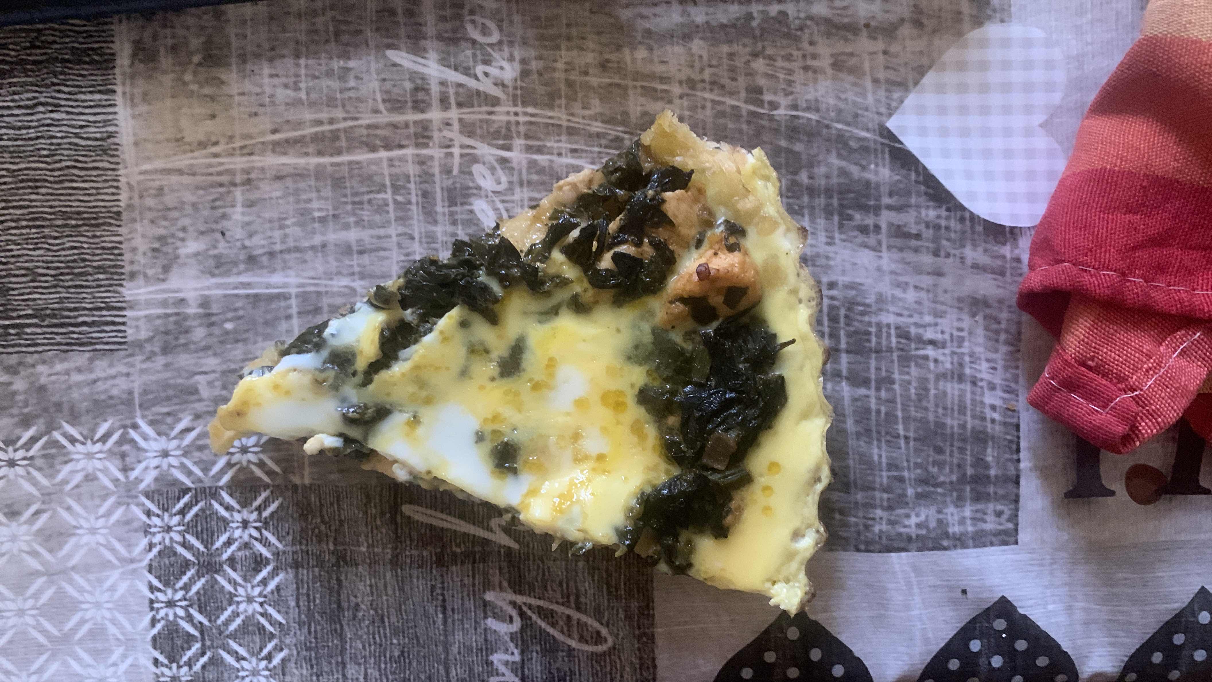 A slice of spinach and cheese quiche, rich in protein and moderate in fats, with a healthy balance of ingredients.