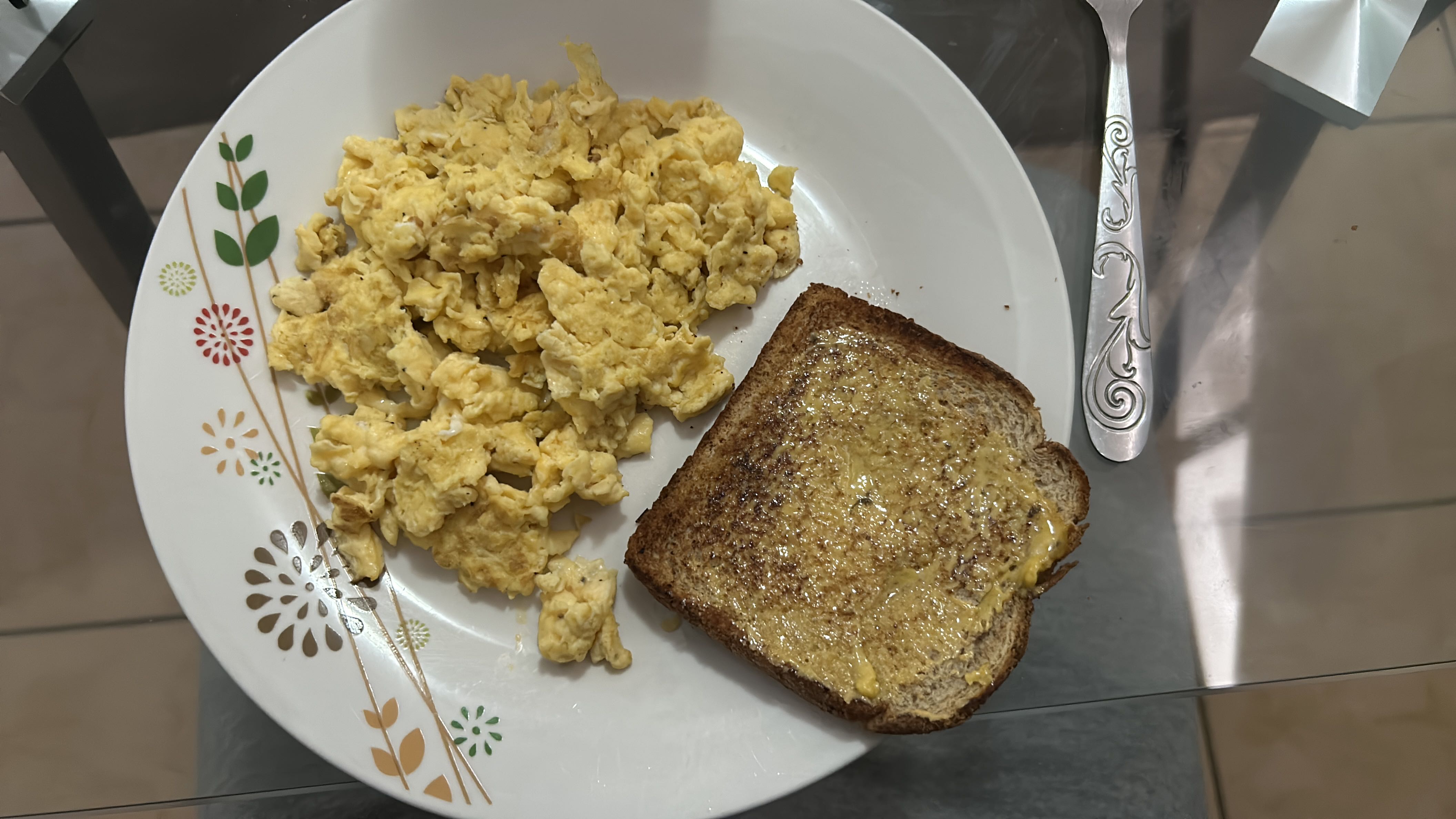A plate containing scrambled eggs and a slice of buttered toast, providing a balanced mix of protein, carbs, and fats.