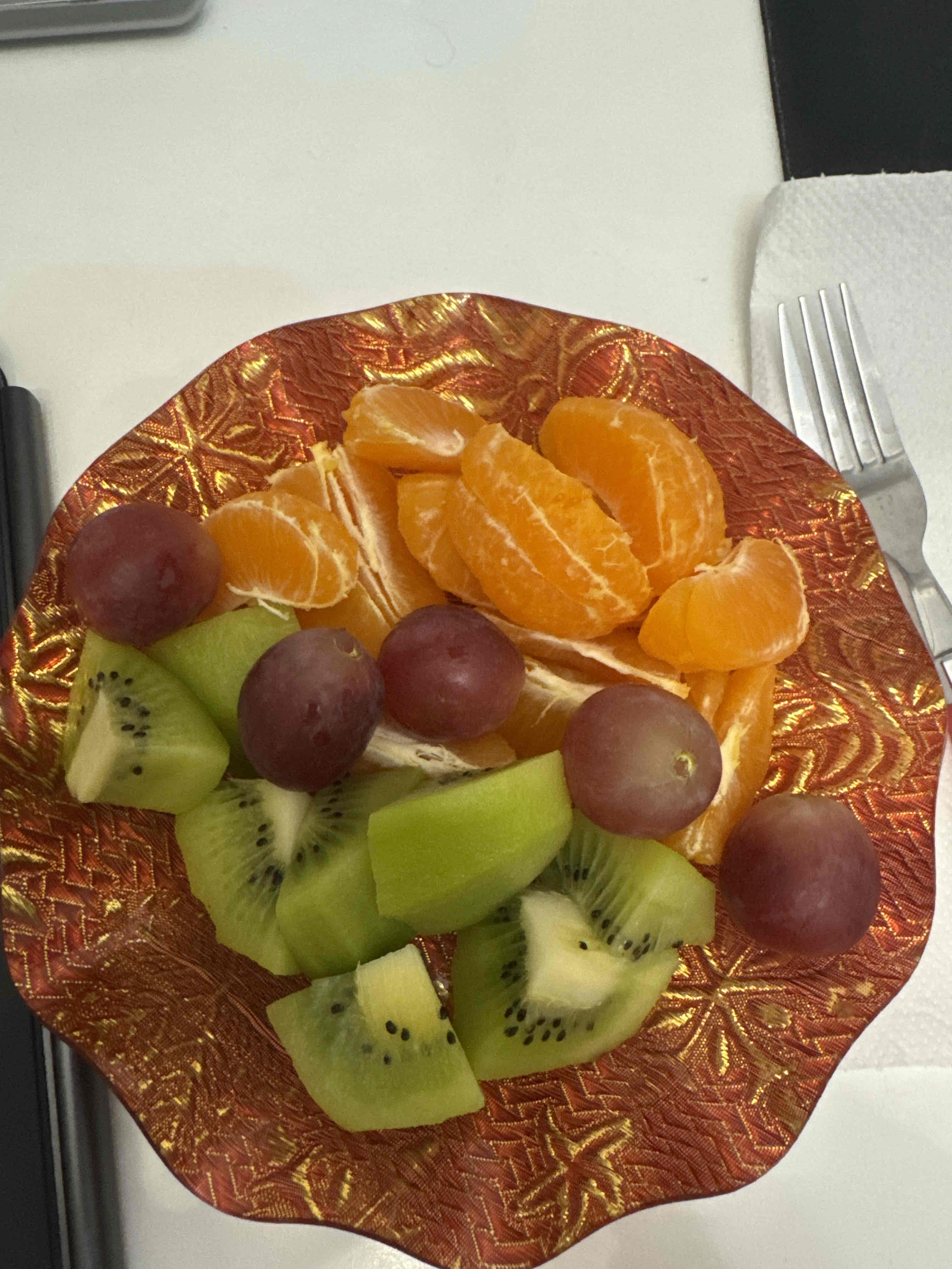 A healthy fruit plate containing oranges, kiwis, and grapes, providing a balanced mix of vitamins and natural sugars.