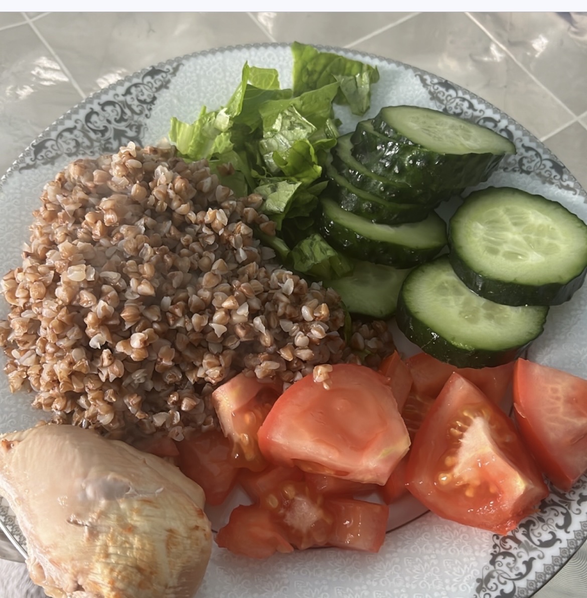 A healthy plate consisting of buckwheat, chicken breast, cucumber, tomato, and lettuce, providing a balanced mix of protein, carbs, and fats.