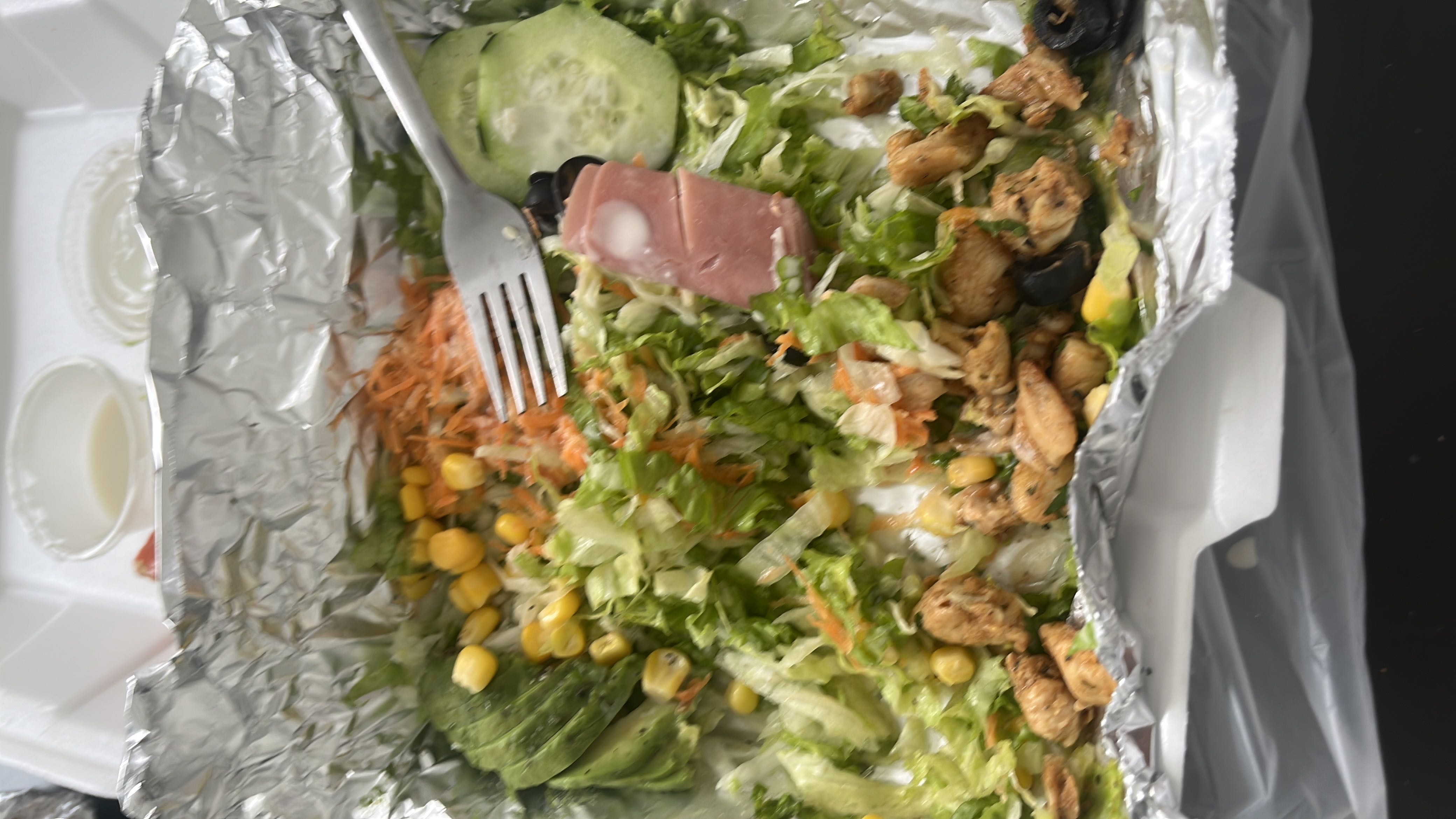 A healthy salad containing chicken, lettuce, carrot, corn, cucumber, ham, and avocado, providing a balanced mix of protein, carbs, and fats.